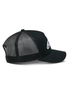 Alpinestars Ageless Trucker pet, zwart, zijaanzicht met gestructureerde kroon en wit geborduurd Astars-logo, gebogen klep en ademende zwarte poly mesh panelen aan de achterkant.