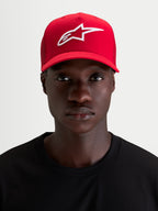 Alpinestars Ageless Snapback Pet, rode sportswear-pet gedragen door een model, met een wit 3D-geborduurd Astars-logo, gebogen klep, gestructureerde kroon en keperstof constructie