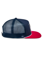 Alpinestars Control Trucker pet, marineblauw en rood, zijprofiel met marineblauw twill voorpaneel en mesh achterpanelen, platte rode klep met wit gevlochten koorddetail, casual motorsport-geïnspireerde hoofdbedekking