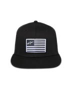 Alpinestars Flag Flat Trucker pet, zwarte pet met platte klep en gestructureerde kroon, centrale rechthoekige patch met witte vlag en Alpinestars-logo, mesh achterkant, casual motorsport-geïnspireerde streetwear