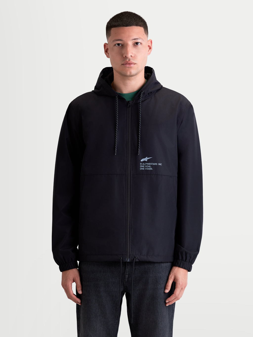 Alpinestars Speeder Resolve Windbreaker jas, lichtgewicht sportswear voor heren op een model, zwart, windbestendige constructie met meshvoering en verstelbare capuchon met 'One Goal. One Vision.' branding op de borst.