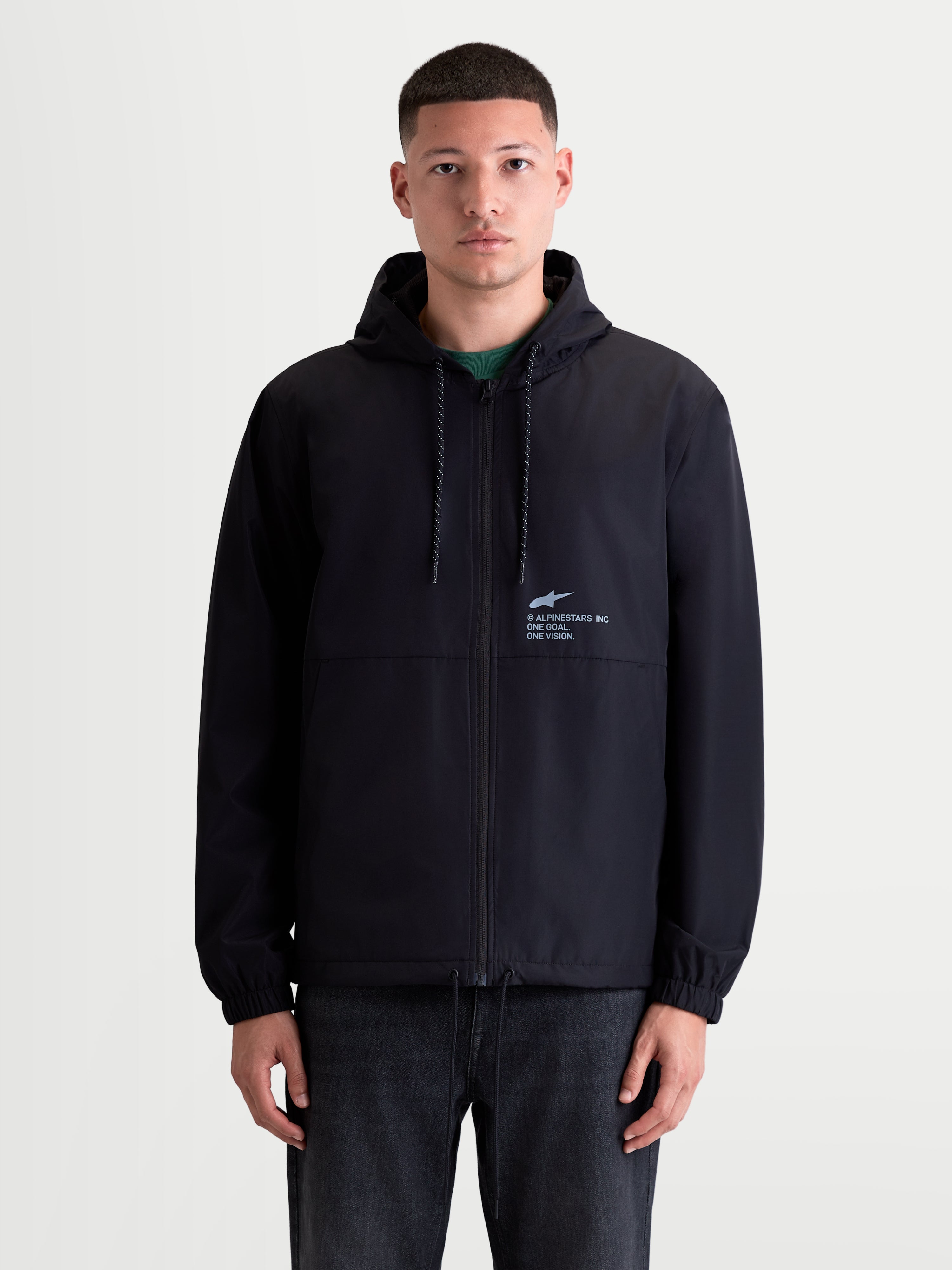 Alpinestars Speeder Resolve Windbreaker jas, lichtgewicht sportswear voor heren op een model, zwart, windbestendige constructie met meshvoering en verstelbare capuchon met 'One Goal. One Vision.' branding op de borst.