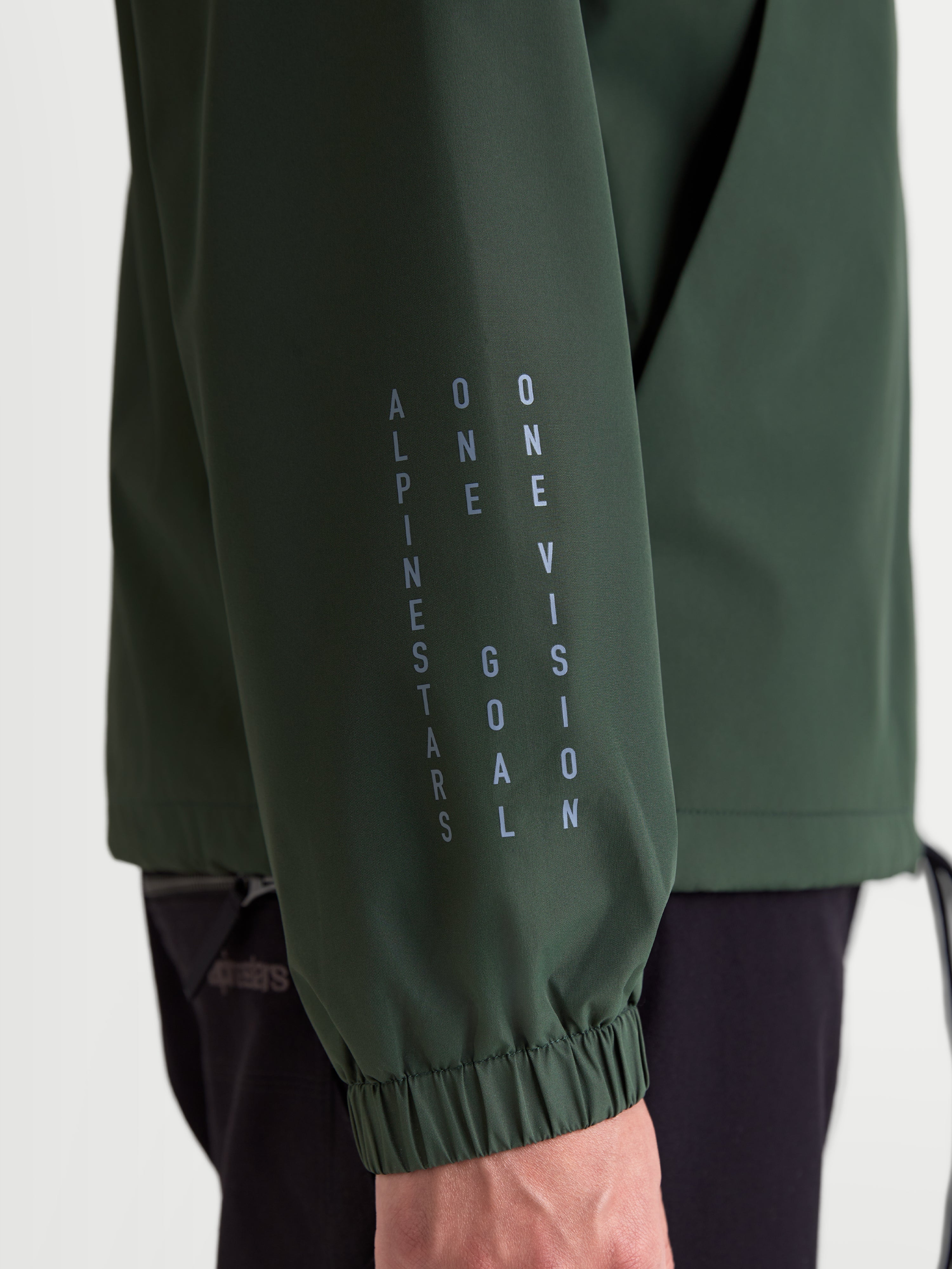 Alpinestars Speeder Resolve Windbreaker Jas, lichtgewicht sportswear windbreaker in groen, close-up van de mouw met verticale Alpinestars-branding en het motto One Goal One Vision, voorzien van een elastische manchet.