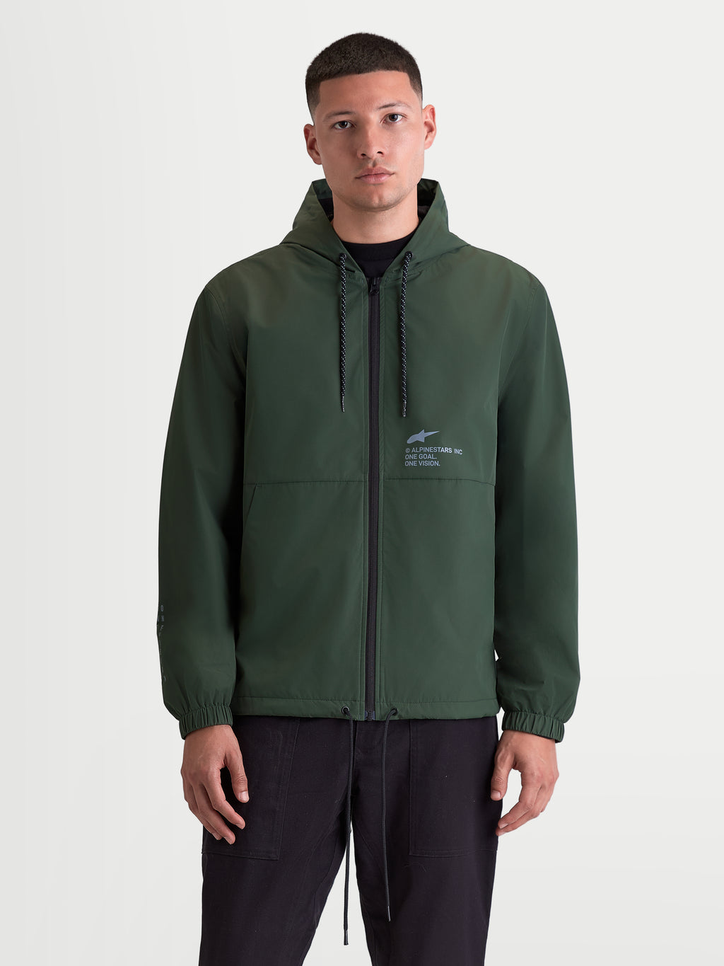 Alpinestars Speeder Resolve windbreakerjas, lichtgewicht sportswear voor urban gebruik, herenjas met capuchon in groen, meshvoering, verstelbare capuchon met trekkoord en volledige rits aan de voorzijde, voorzien van Alpinestars-branding op de borst, vooraanzicht op model.