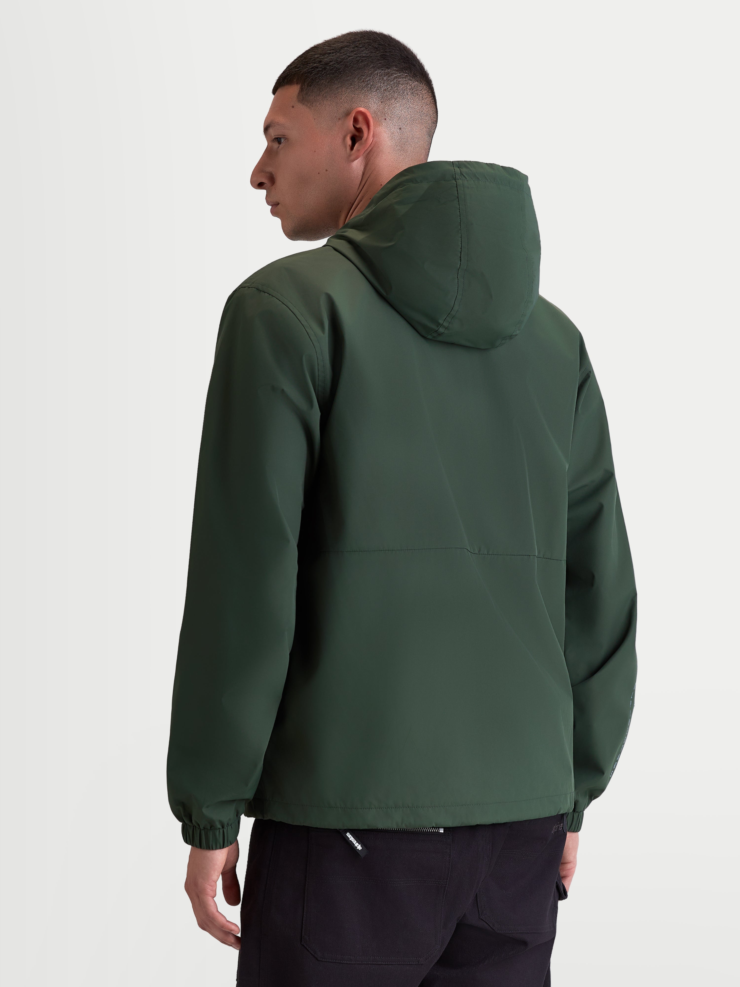 Alpinestars Speeder Resolve Windbreaker Jas, lichtgewicht sportswear met capuchon voor stedelijk gebruik, groen, winddicht 100% polyester met meshvoering, achteraanzicht op model met focus op het strakke rugontwerp en elastische manchetten.