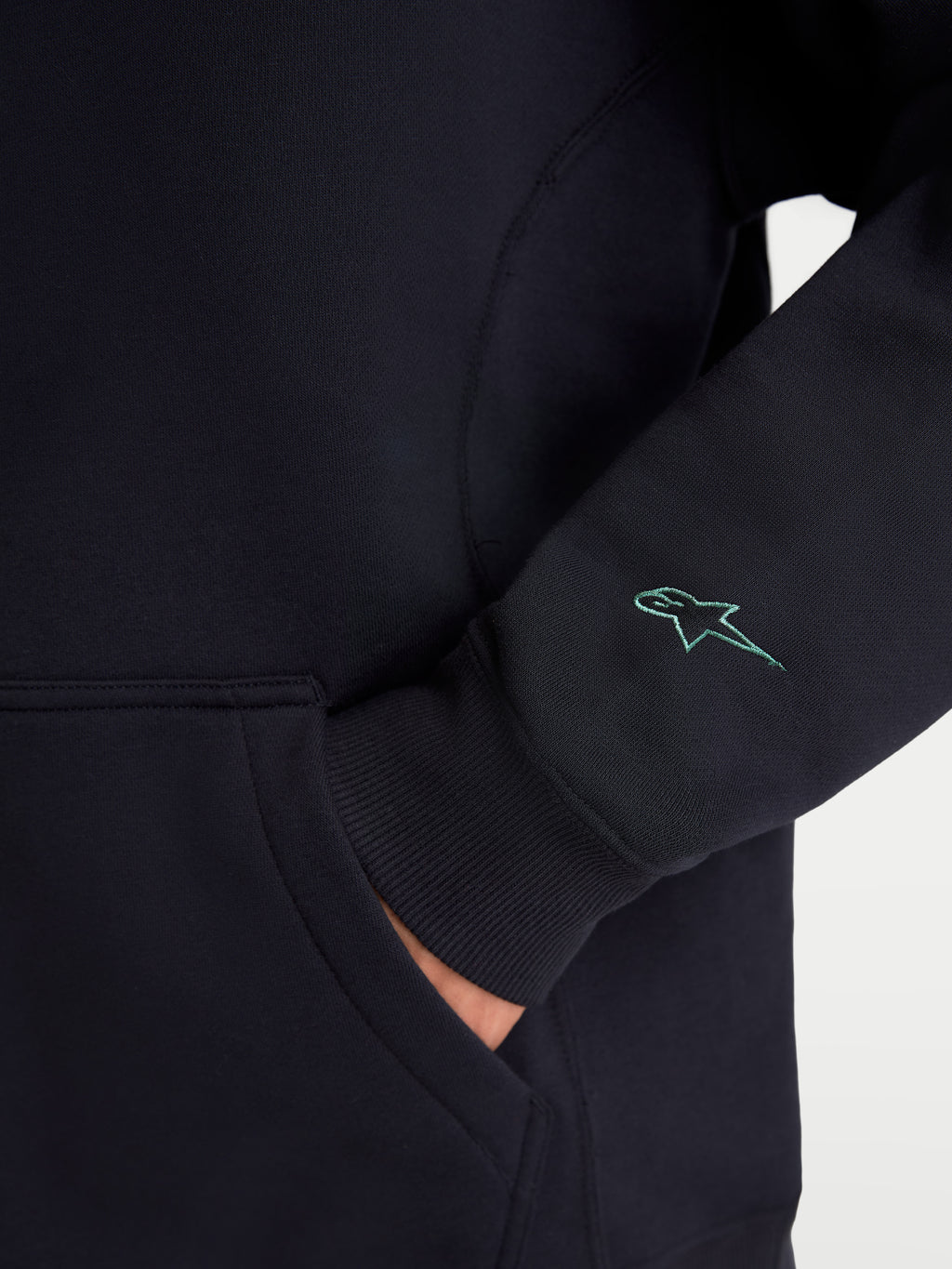 Alpinestars Guise Oversized Crew, sportswear fleece pullover, zwart, detail van het geborduurde Astars-logo op de mouw, geribde manchetten en kangoeroezak, mix van katoen en gerecycled polyester, relaxte oversized pasvorm.
