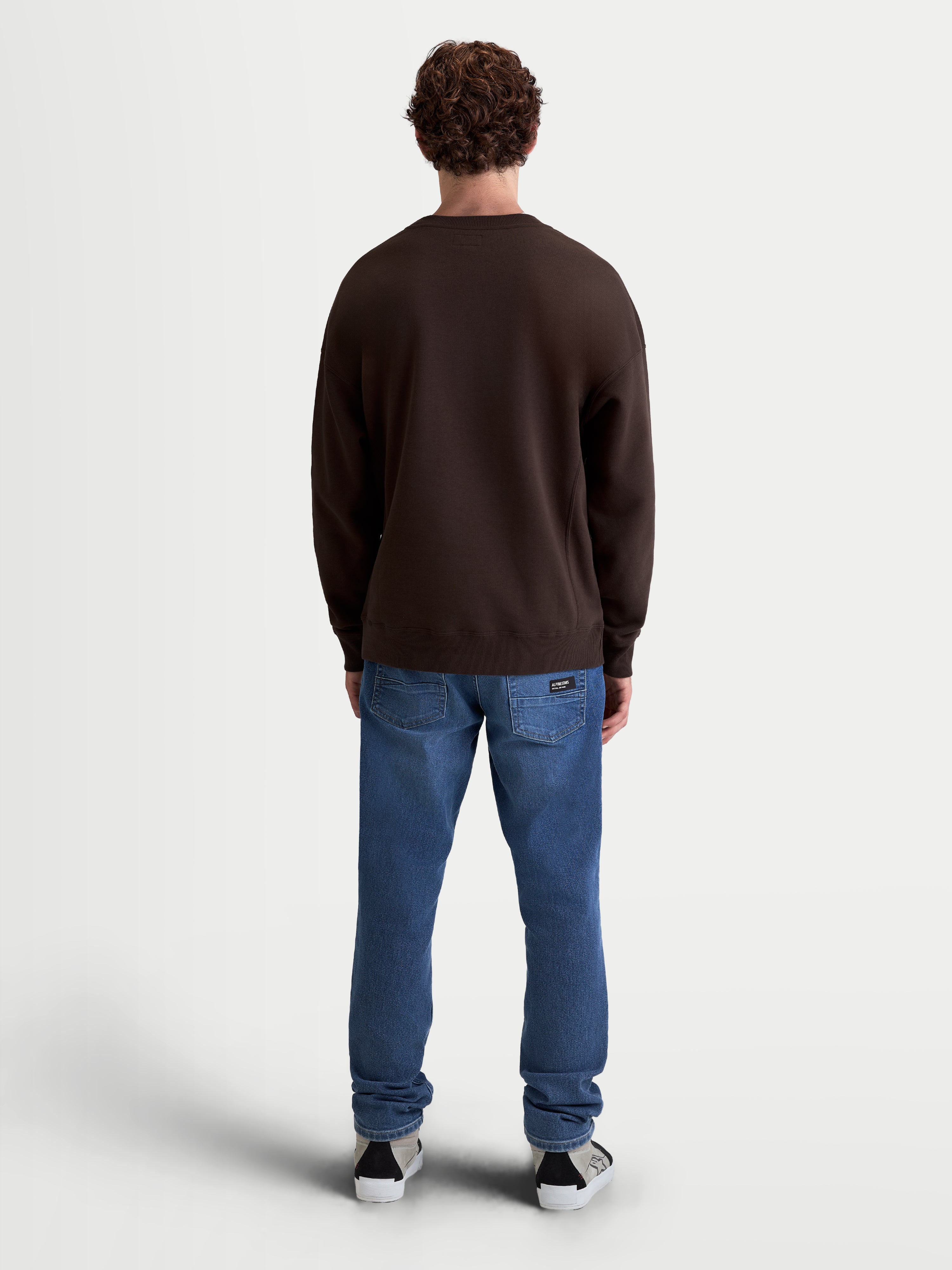 Alpinestars Guise Oversized Crew, bruine sportswear fleece pullover, oversized pasvorm, achteraanzicht op model, katoen en gerecycled polyester mix, geribde boorden en zoom.