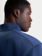 Alpinestars Apera Half-Zip sweatshirt, sportswear pullover in blauw, close-up achteraanzicht op model met tonale HD-logo opdruk op de schouder en premium tri-blend fleece stof.