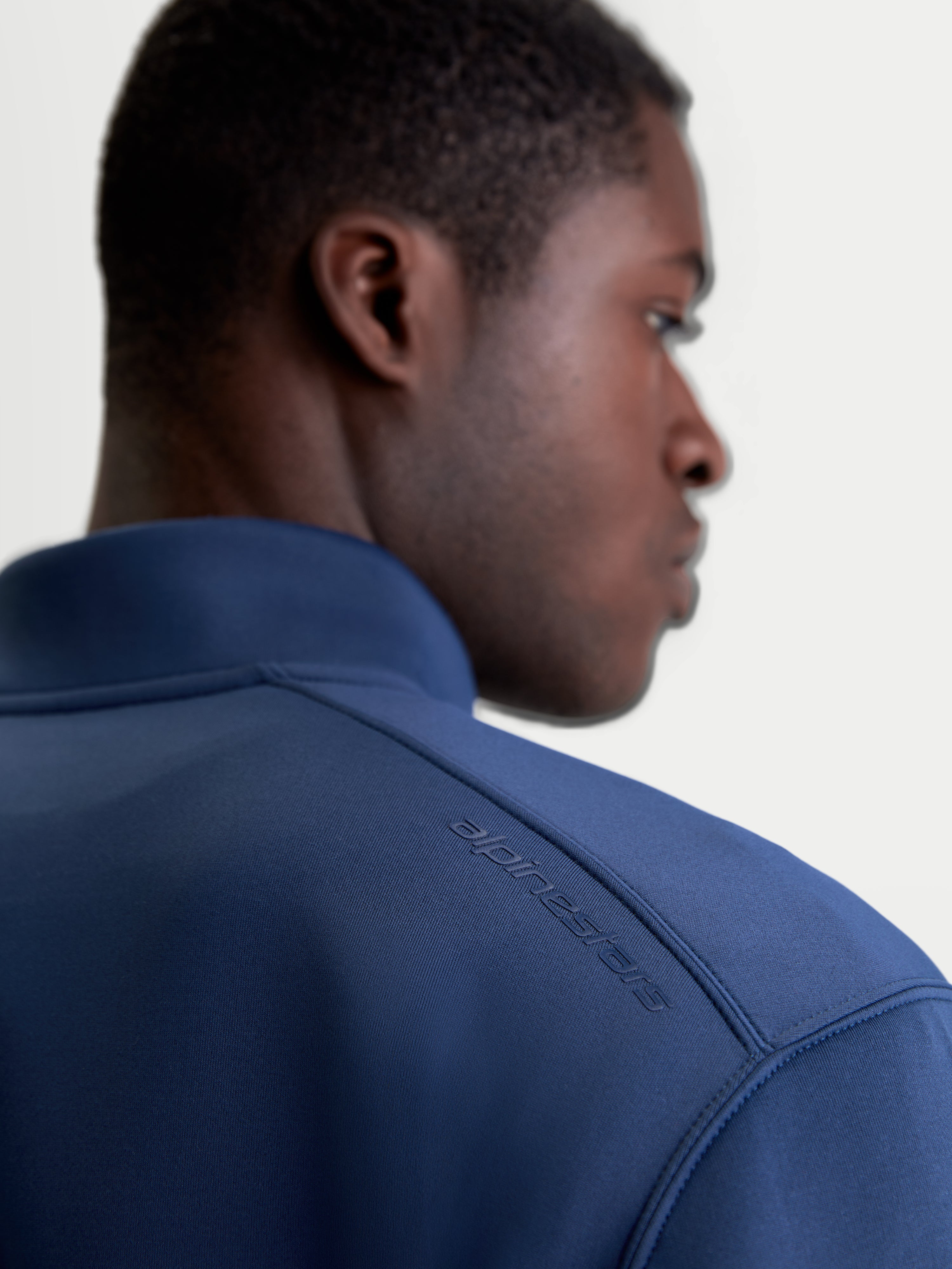 Alpinestars Apera Half-Zip sweatshirt, sportswear pullover in blauw, close-up achteraanzicht op model met tonale HD-logo opdruk op de schouder en premium tri-blend fleece stof.