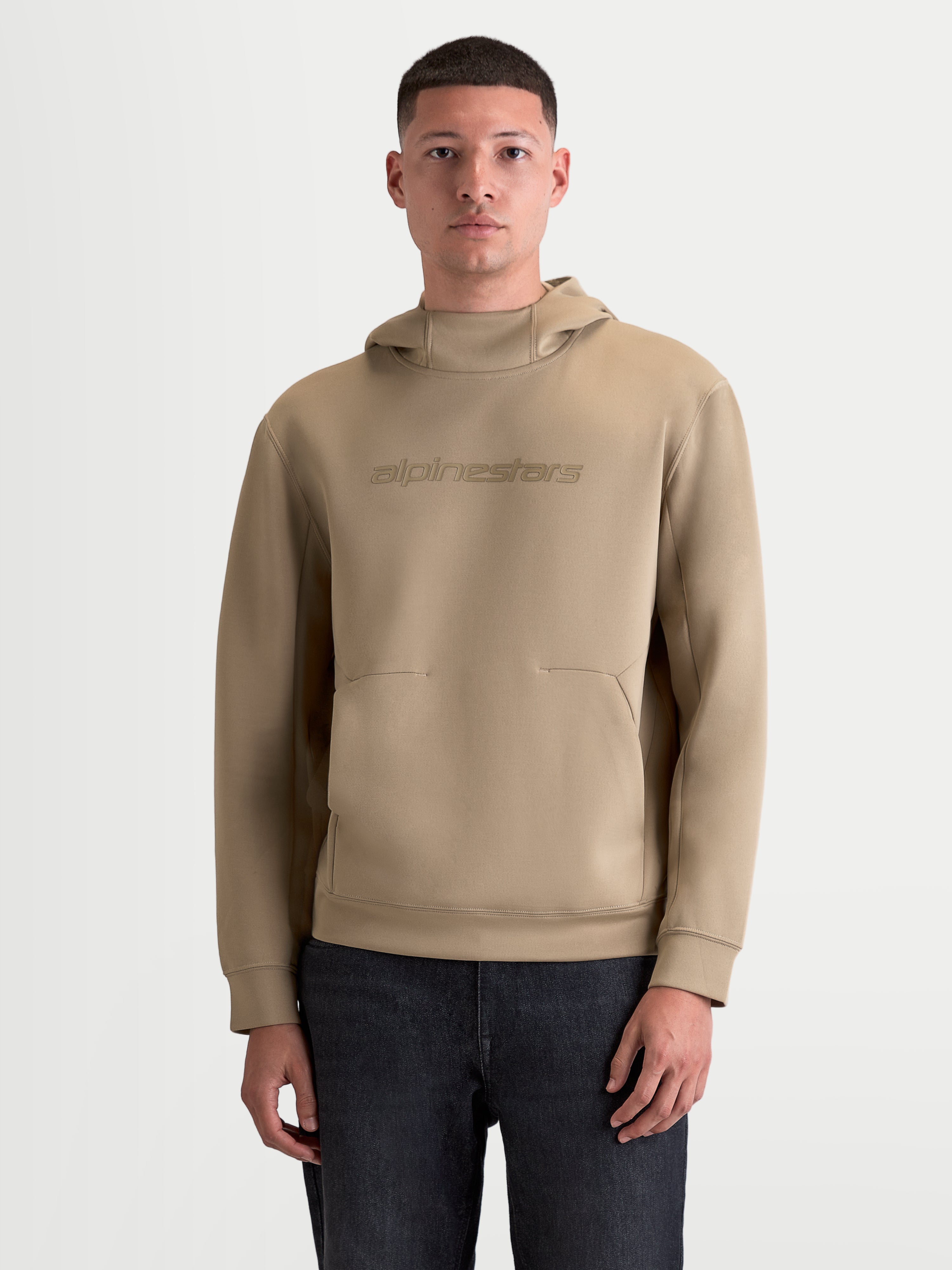 Alpinestars Datrix Hoodie, premium sportswear pullover voor heren en dames, bruin, tonale Alpinestars-branding, capuchon met meshvoering en tri-blend dubbelzijdige fleece, motorsport-geïnspireerde casual kleding op model