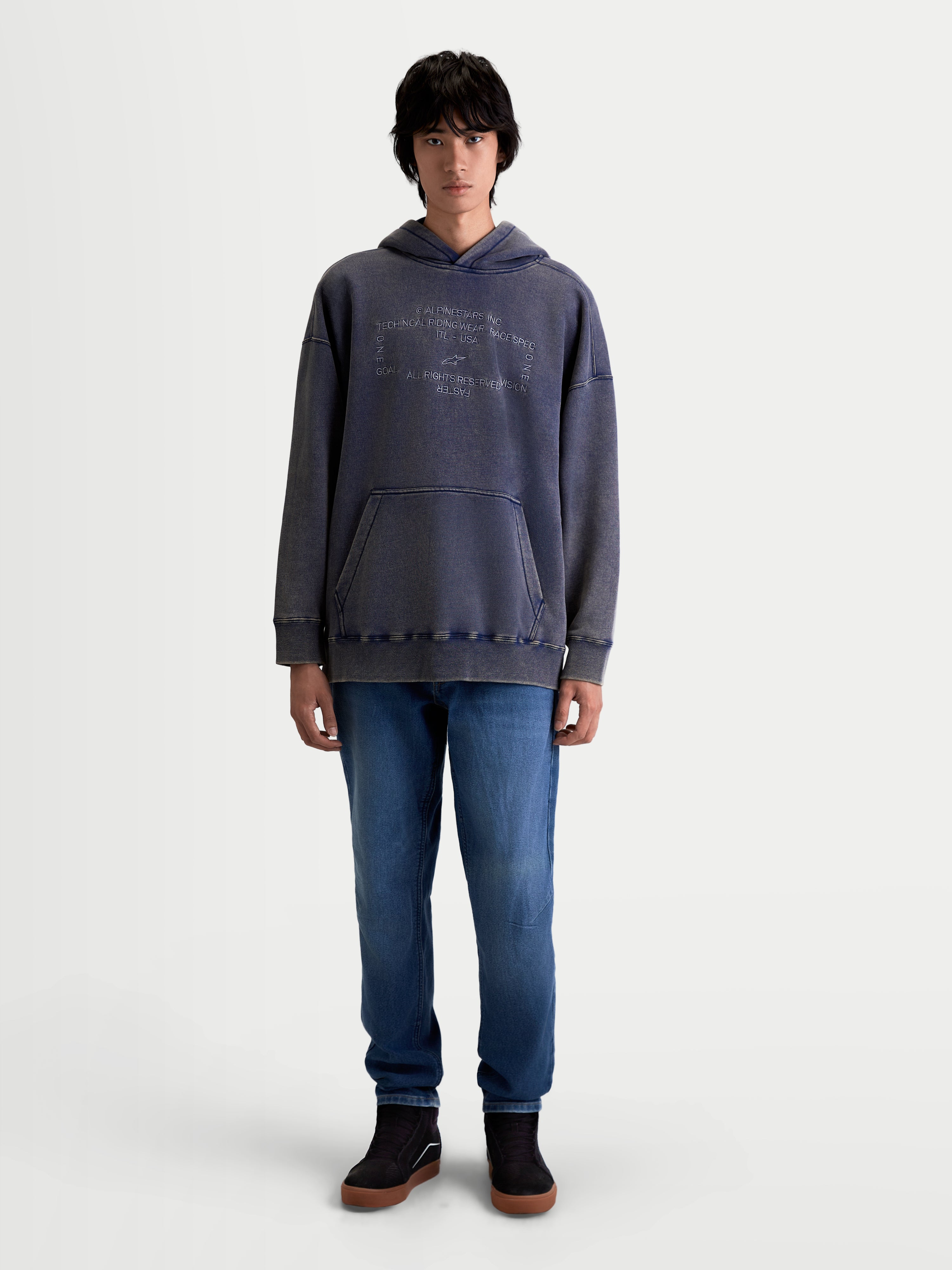 Alpinestars Infinite Washed Oversized Hoodie, casual sportswear hoodie gedragen door een model, gewassen blauw met een snow-wash-afwerking, voorzien van een kangoeroezak en geborduurd Alpinestars-woordmerk op de borst, ontspannen oversized pasvorm.