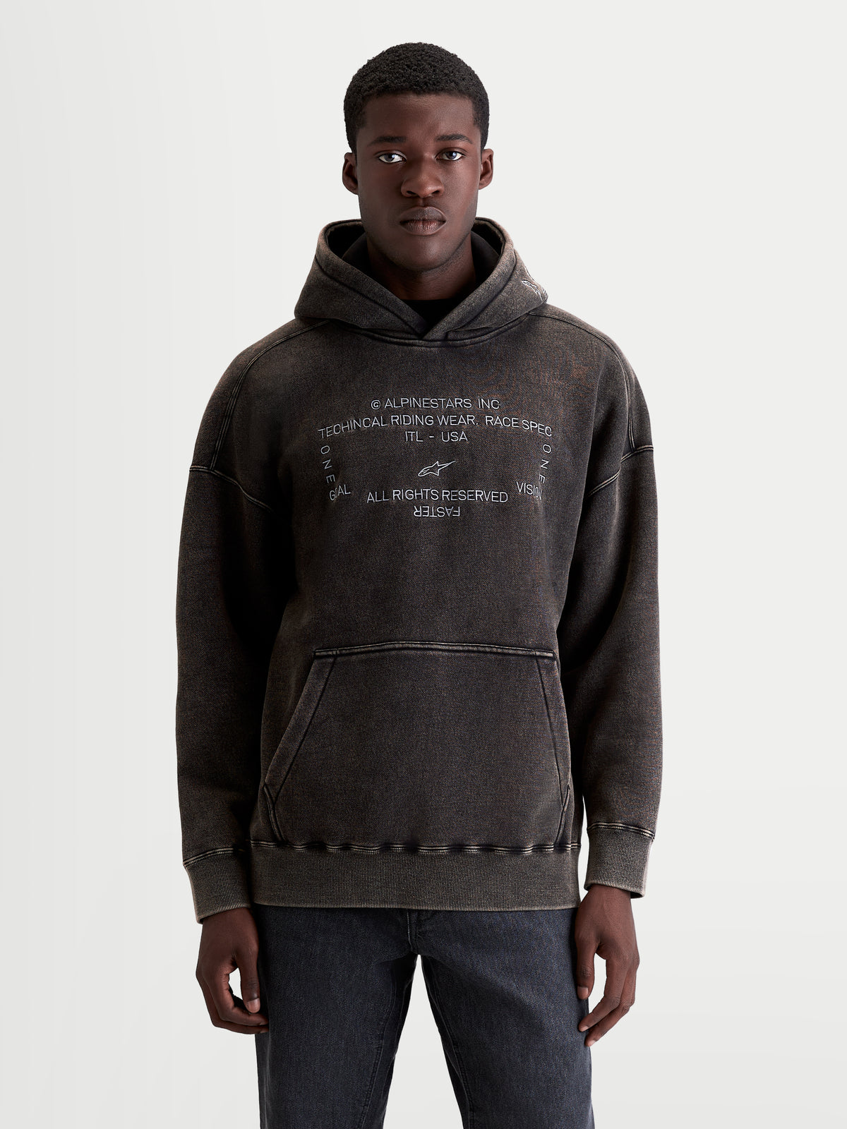 Alpinestars Infinite Washed Oversized hoodie, casual sportswear pullover, gewassen zwart, fleece met snow-wash afwerking, voorzien van kangoeroezak en wit geborduurd Alpinestars-logo, vooraanzicht op model.