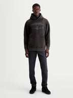 Alpinestars Infinite Washed Oversized Hoodie, Sportswear Pullover in Washed Black. This premium fleece hoodie features a snow-wash finish, kangaroo pocket, and technical branding embroidery on the chest. Shown on a model to demonstrate the relaxed, oversized fit for casual lifestyle wear.