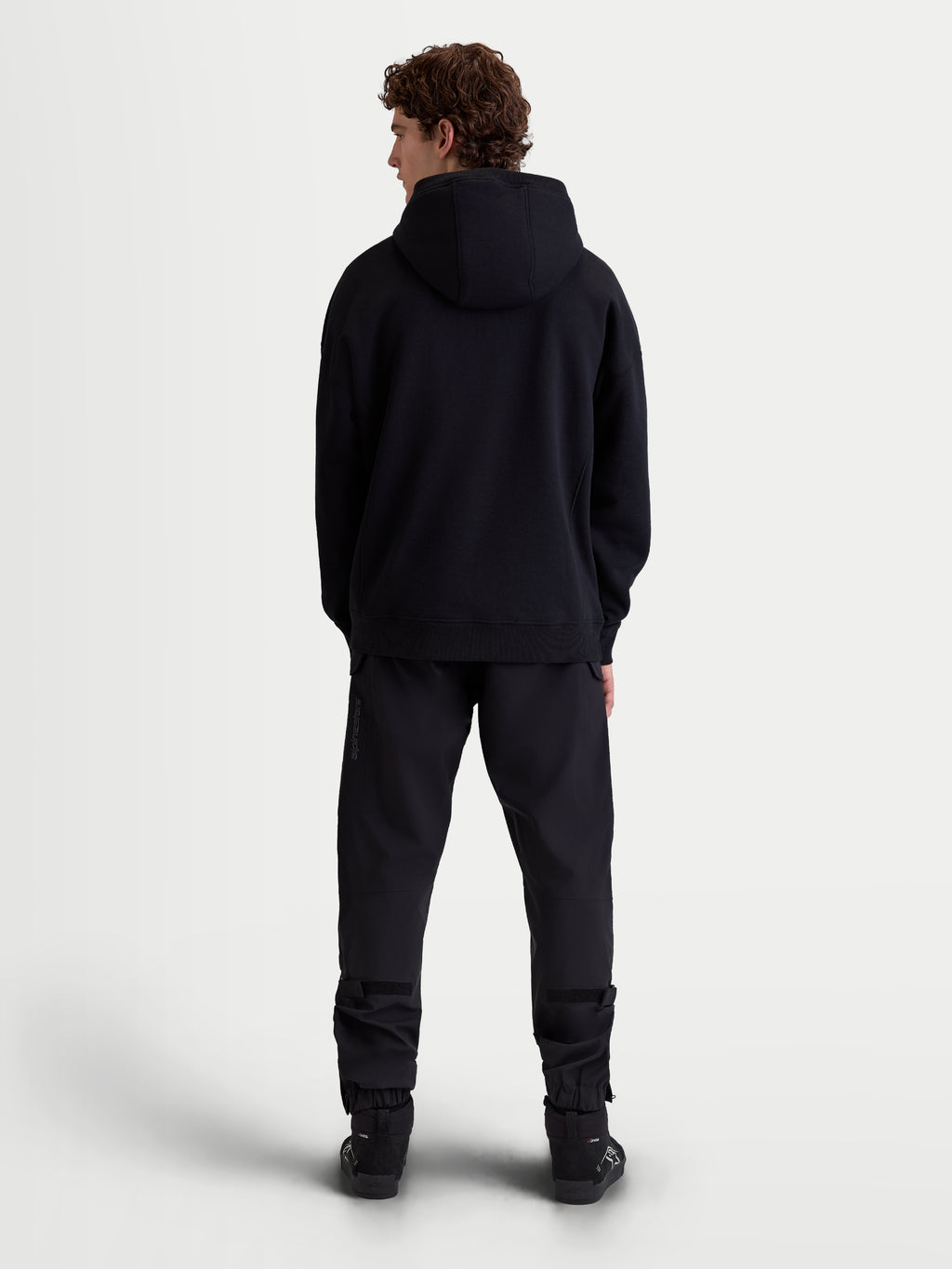 Alpinestars Shaw Oversized hoodie, zwarte casual sportswear-pullover, volledig achteraanzicht op model, relaxed silhouet met zelfgevoerde capuchon en geribde boorden, zachte fleece constructie.