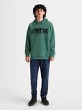 Alpinestars Shaw oversized hoodie, groene sportswear-pullover van fleece met een zwart getextureerd logo op de borst, oversized pasvorm, voorzien van kangoeroezak en zelfgevoerde capuchon, katoenmix met gerecycled polyester, getoond op model.
