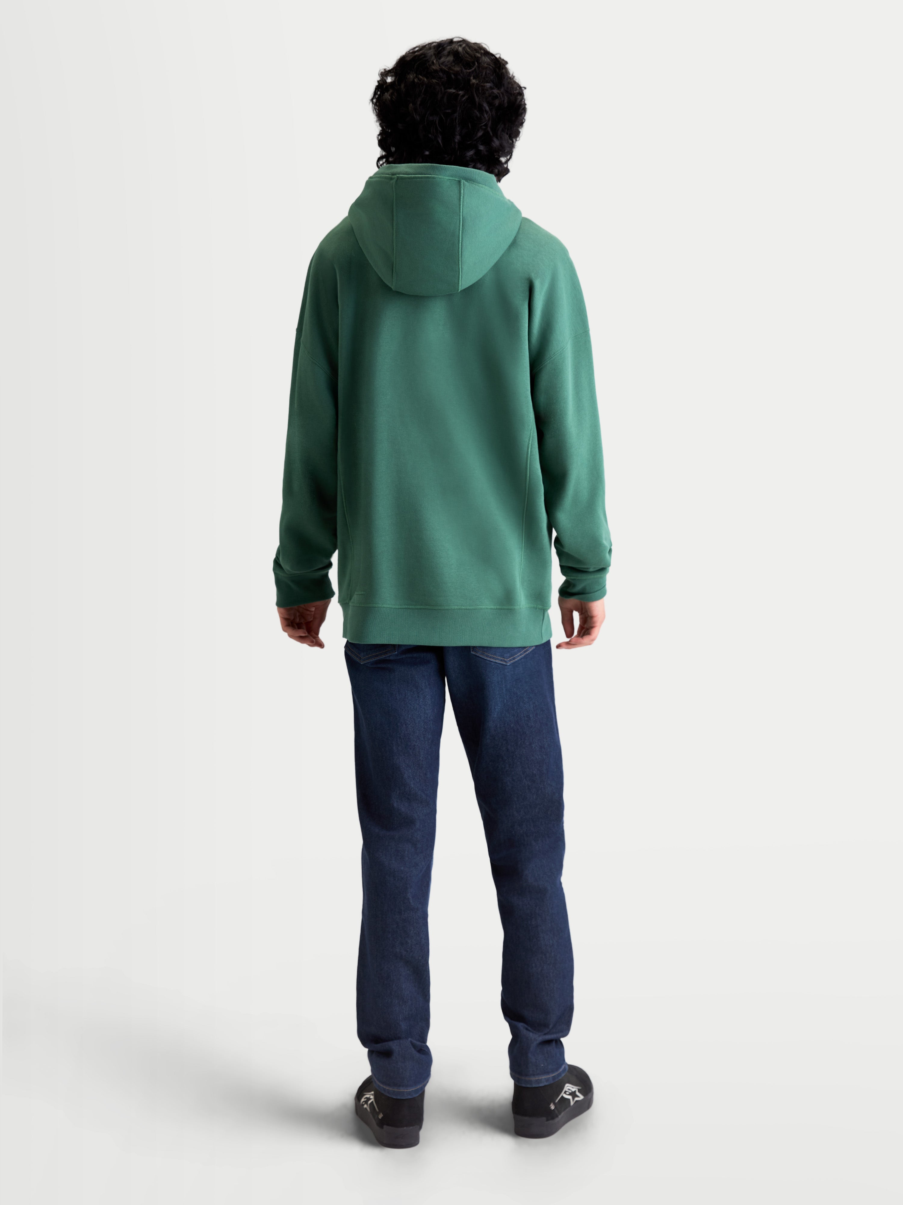 Alpinestars Shaw Oversized hoodie, groene sportswear-pullover, achteraanzicht op model, unisex relaxte pasvorm, zachte fleece van katoen en gerecycled polyester, voorzien van een zelfgevoerde capuchon en geribde boorden voor dagelijks comfort.