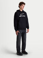 Alpinestars Prelude Oversized Hoodie, heren sportswear fleece pullover, zwart met wit puffprint-logo op de borst en mouw, relaxte oversized pasvorm en kangoeroezak, getoond op een model.