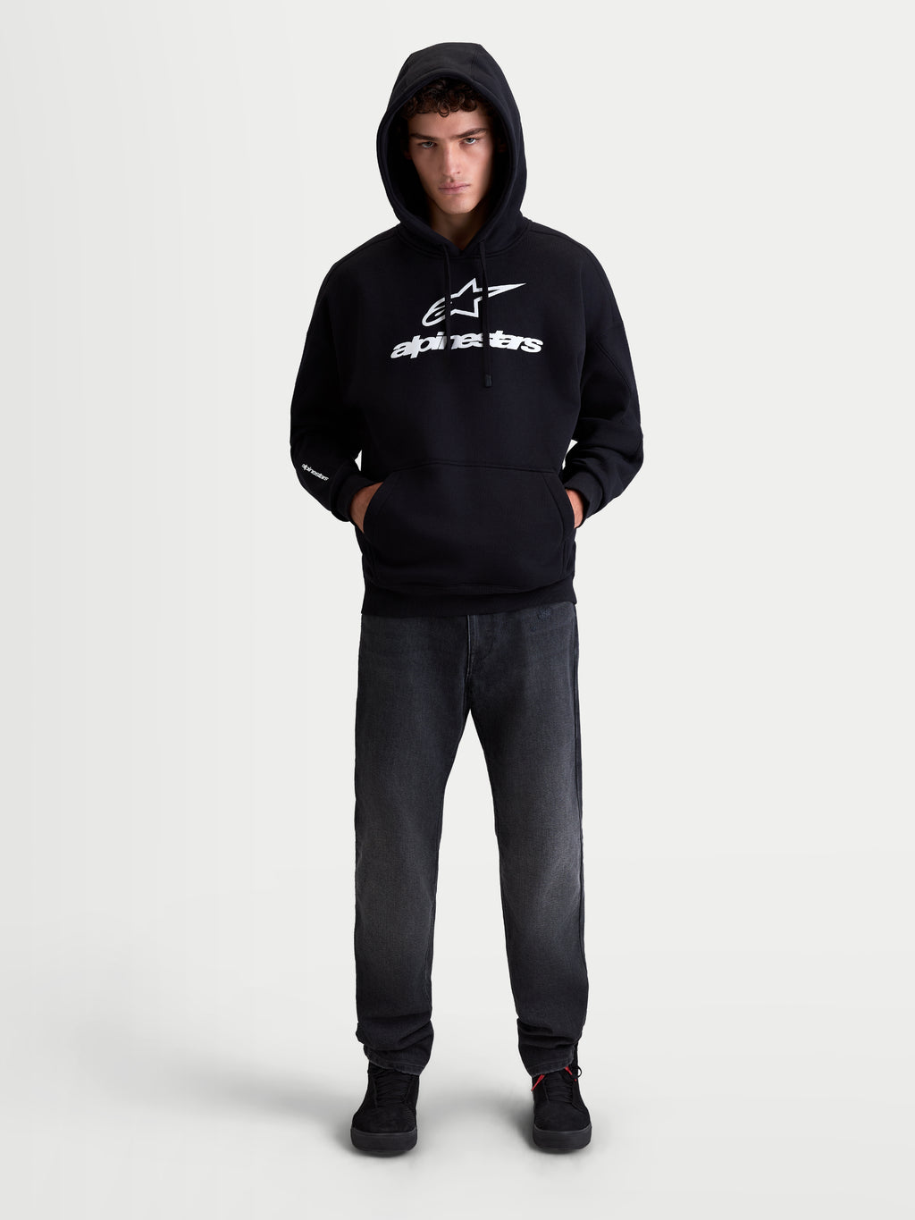 Alpinestars Prelude oversized hoodie, sportswear fleece pullover, unisex, zwart en wit, katoen en gerecycled polyester, ontspannen oversized pasvorm met kangoeroezak en opvallende puffprint-logo's op de borst en mouw, getoond op model.