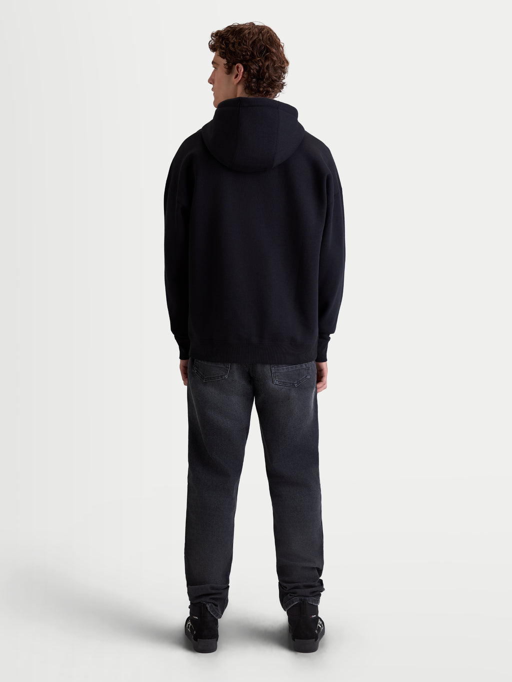 Alpinestars Prelude Oversized Hoodie, sportswear fleece pullover, zwart, achteraanzicht op model, ontspannen oversized pasvorm met verlaagde schouders en geribde zoom, premium katoenmix, casual sportswear voor dagelijks gebruik.