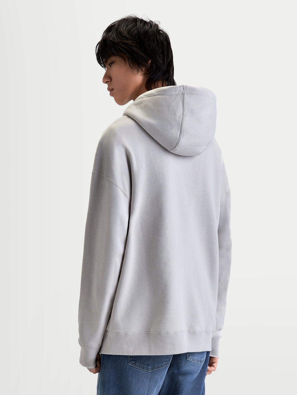 Alpinestars Prelude oversized hoodie, grijze sportswear fleecepullover voor heren en dames, ontspannen silhouet met gevoerde capuchon en mouwnaden, achteraanzicht op model.