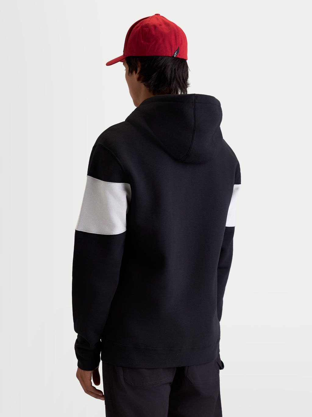 Alpinestars Cubic hoodie, sportswear pullover fleece, zwart en wit, met kleurgeblokte mouwen, achteraanzicht op model, blend van katoen en gerecycled polyester, casual motorsportstijl.