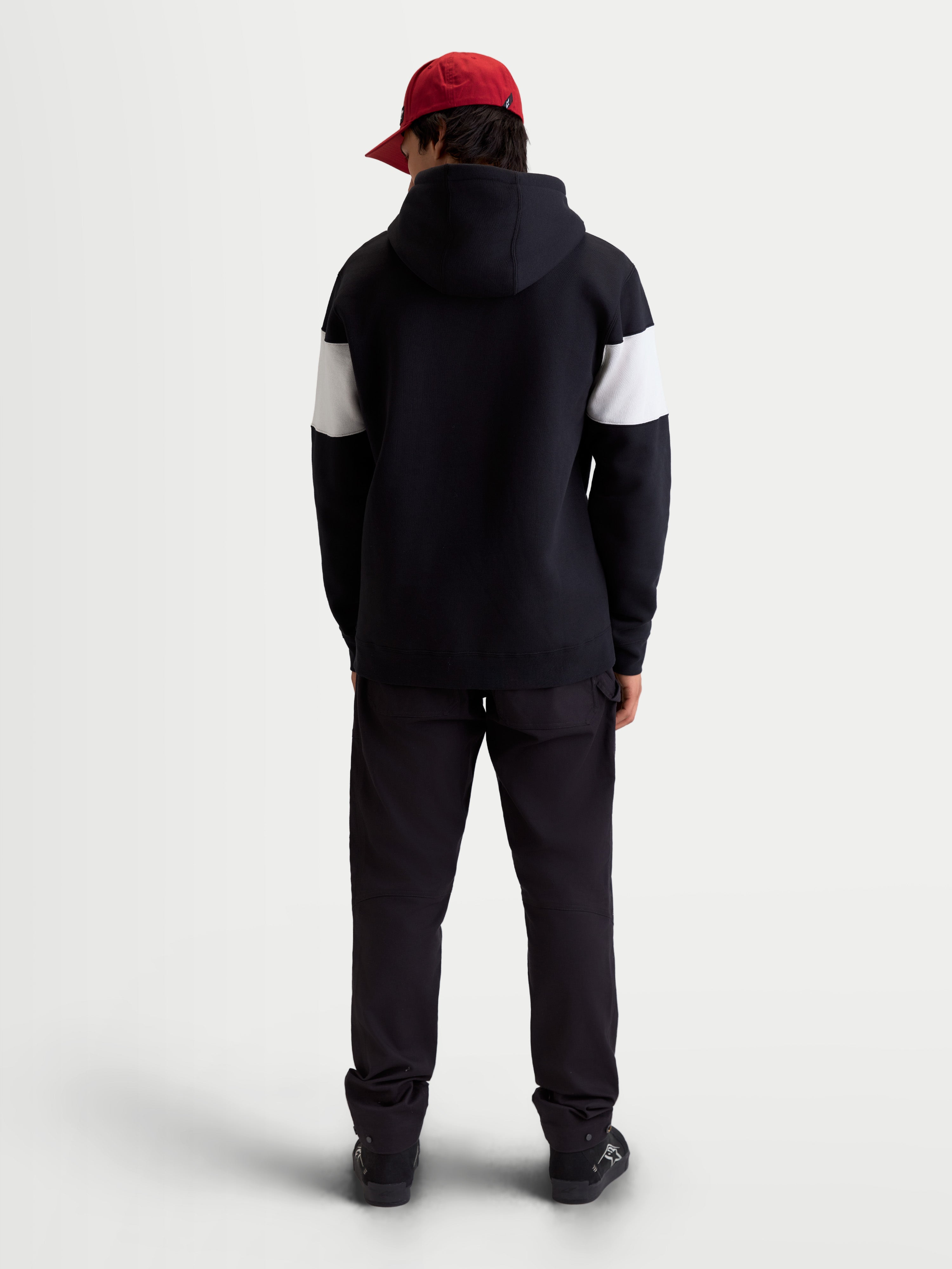 Alpinestars Cubic hoodie, unisex sportswear pullover fleece, kleurgeblokte mouwen in zwart en wit, achteraanzicht op model, premium katoenmix constructie, casual kleding voor na het motorrijden.