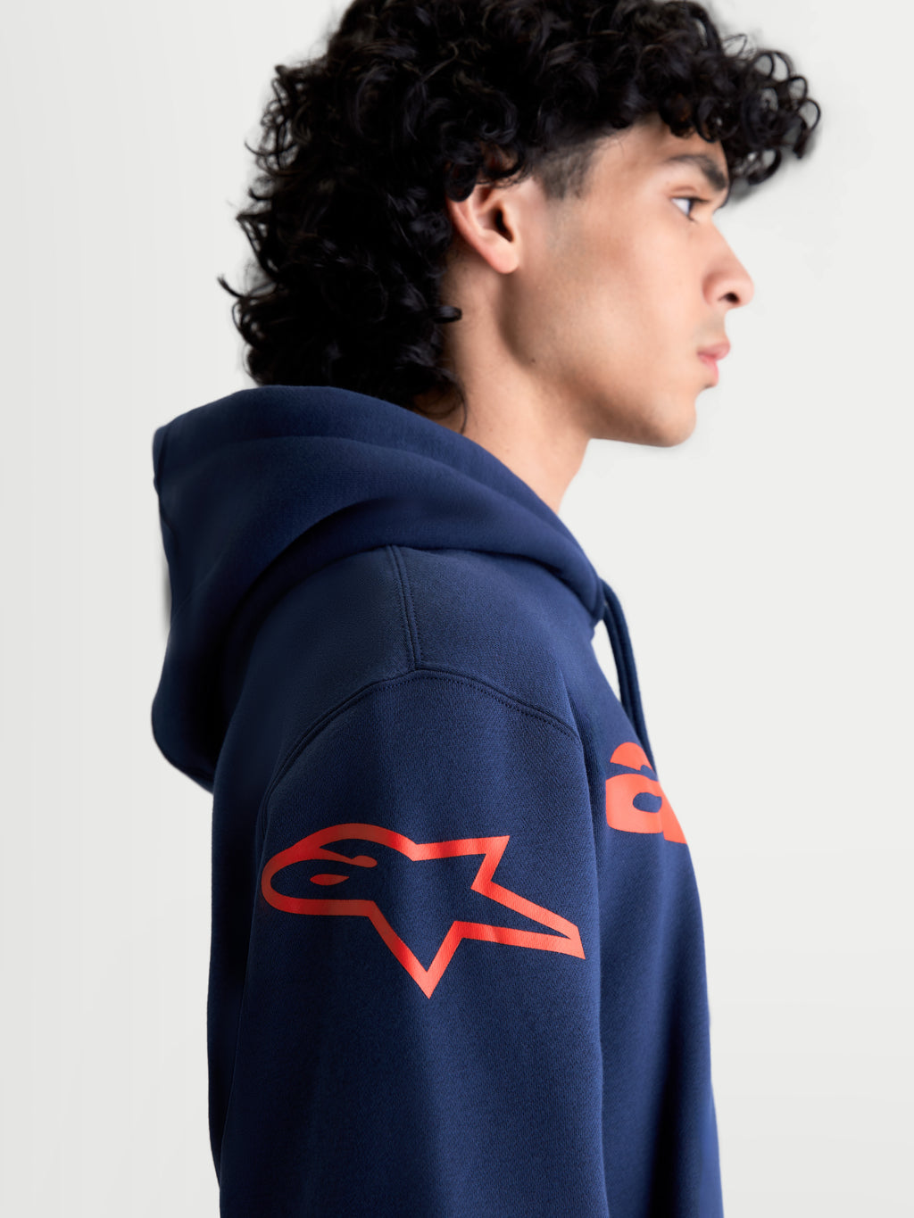 Alpinestars Velocifier hoodie, heren-sportswear pullover met capuchon, marineblauw en rood, zijprofiel met het rode Astars-logo op de schouder, comfortabele fleece voor motorsportliefhebbers.