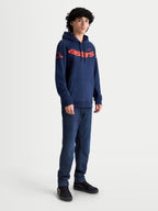Alpinestars Velocifier Hoodie, heren-sportswear pullover fleece, marineblauw en oranje, met opvallend Astars-woordmerk op de borst en logo's op de schouders, getoond op een model voor casual motorsport-geïnspireerde vrijetijdskleding.