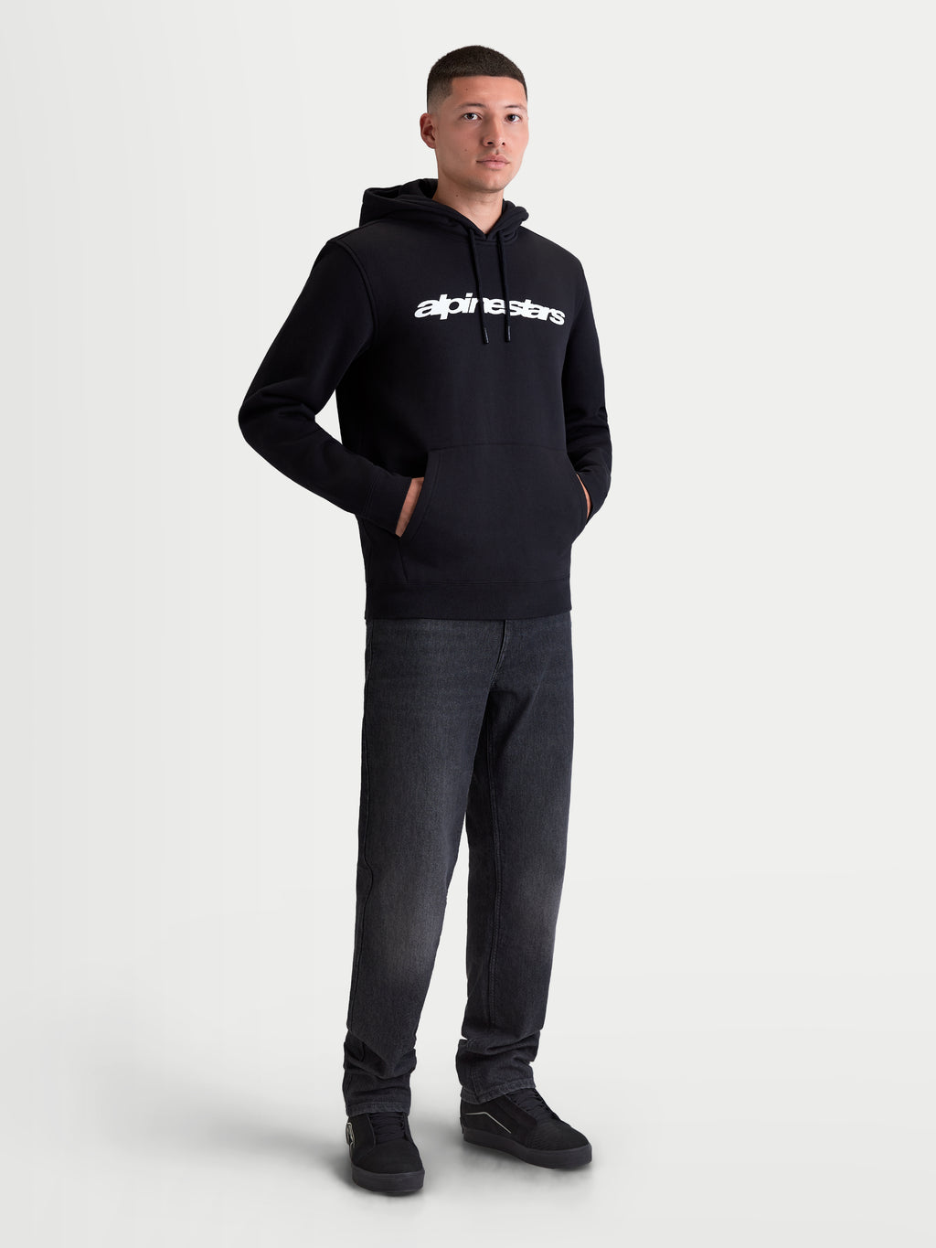 Alpinestars Race Wordmark hoodie, heren sportswear pullover fleece, zwart en wit, voorzien van een wit lineair logo op de borst, gevoerde capuchon met trekkoorden en een kangoeroezak aan de voorzijde, gedragen door model.