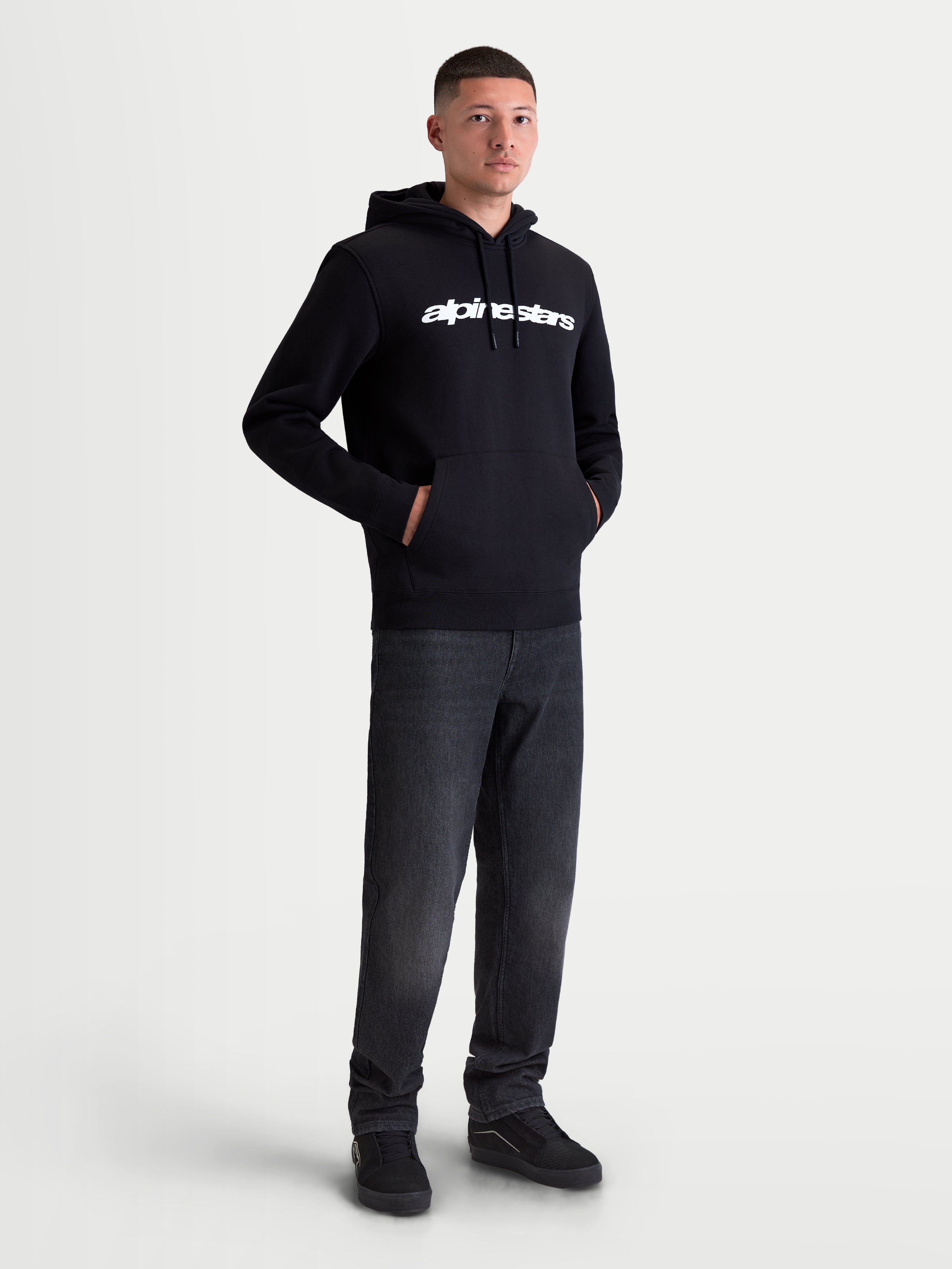Alpinestars Race Wordmark hoodie, heren sportswear pullover fleece, zwart en wit, voorzien van een wit lineair logo op de borst, gevoerde capuchon met trekkoorden en een kangoeroezak aan de voorzijde, gedragen door model.