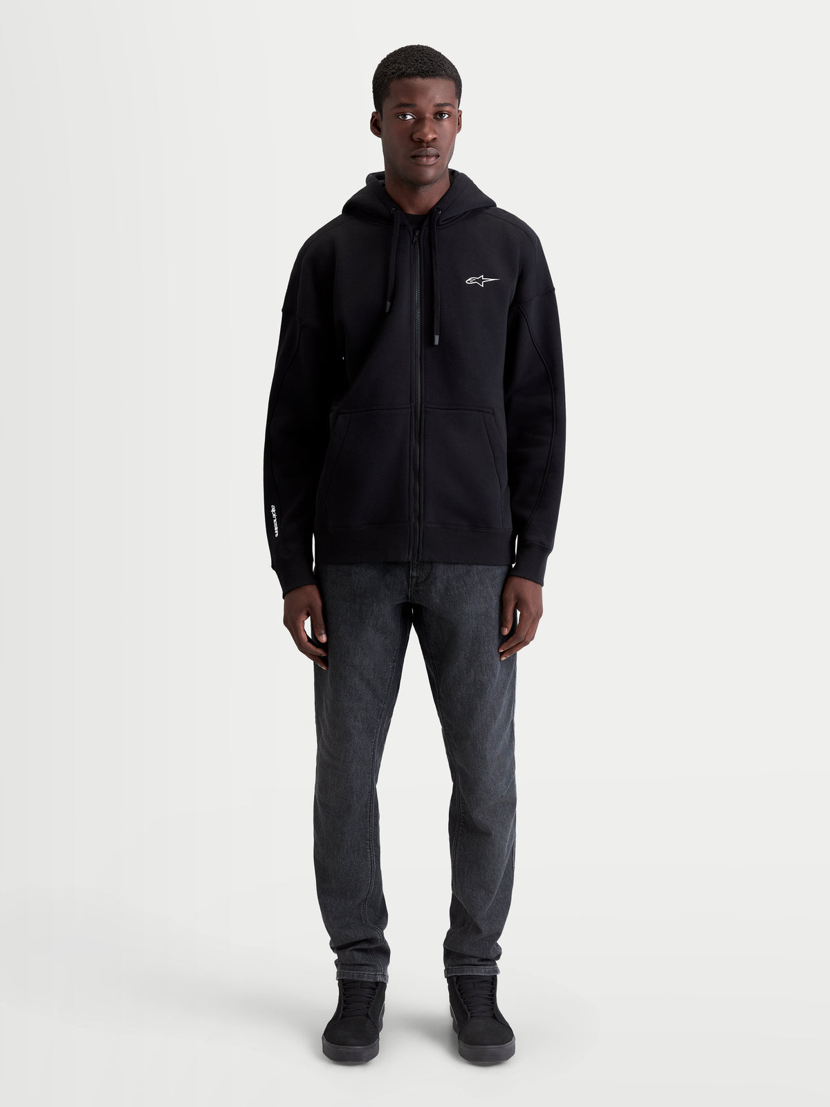 Alpinestars Entity Oversized Hoodie, premium sportswear fleece met ritssluiting, zwart, unisex relaxed fit, voorzien van Vislon-rits, zelfgevoerde capuchon en kangoeroezak, katoen en gerecycled polyester met geborduurde logo's, volledige on-model weergave.