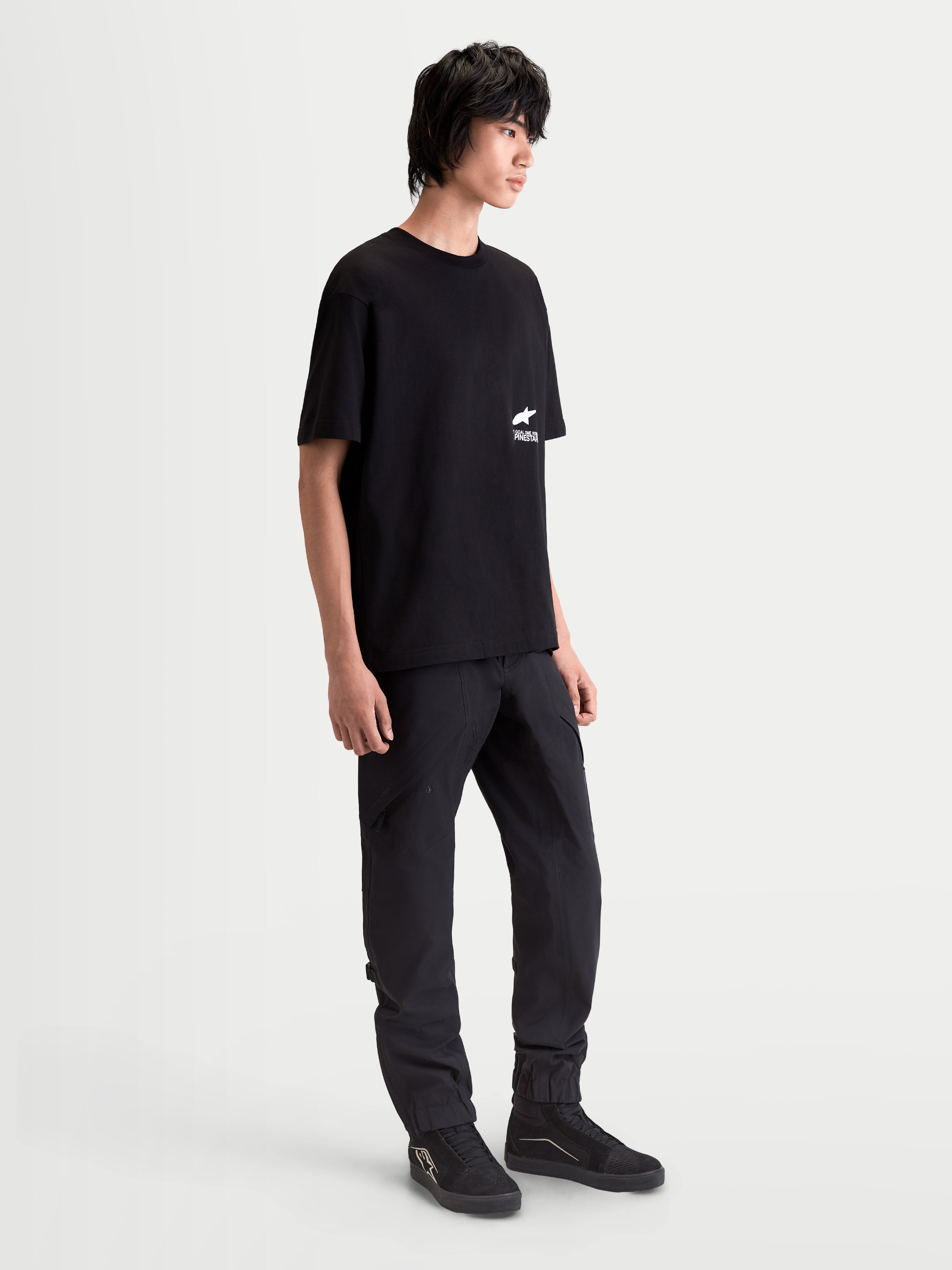 Alpinestars Institute Oversized CSF Tee, Men's Sportswear Short Sleeve T-Shirt in Black, featuring a relaxed oversized fit and white chest logo graphic, worn by a model for a casual motorsport-inspired look.