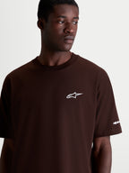 Alpinestars Mandate Oversized CSF t-shirt met korte mouwen, bruin met wit Astars-logo op de borst, casual sportswear, oversized pasvorm, katoen-polyester mix, detailopname op model.