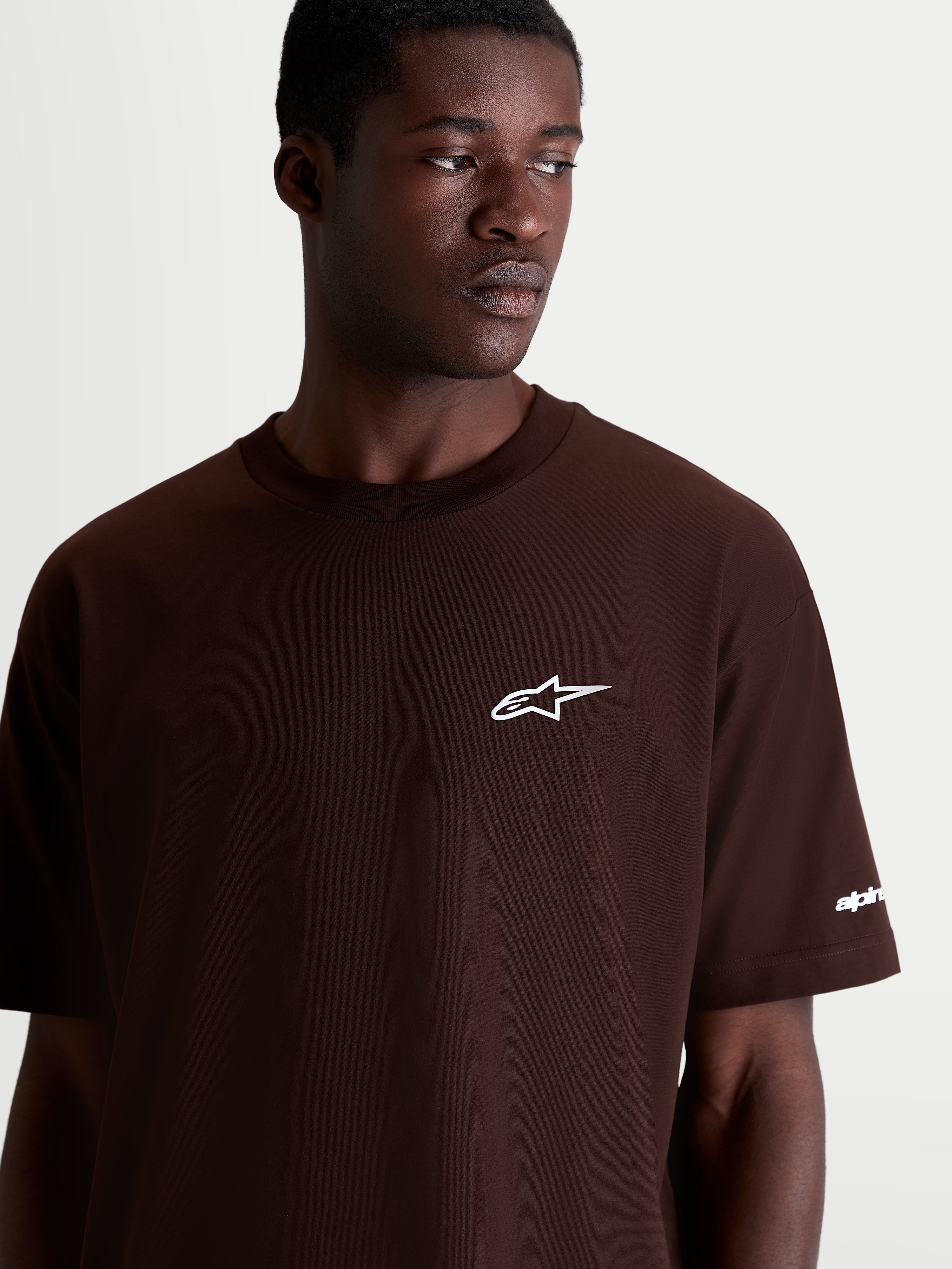 Alpinestars Mandate Oversized CSF t-shirt met korte mouwen, bruin met wit Astars-logo op de borst, casual sportswear, oversized pasvorm, katoen-polyester mix, detailopname op model.