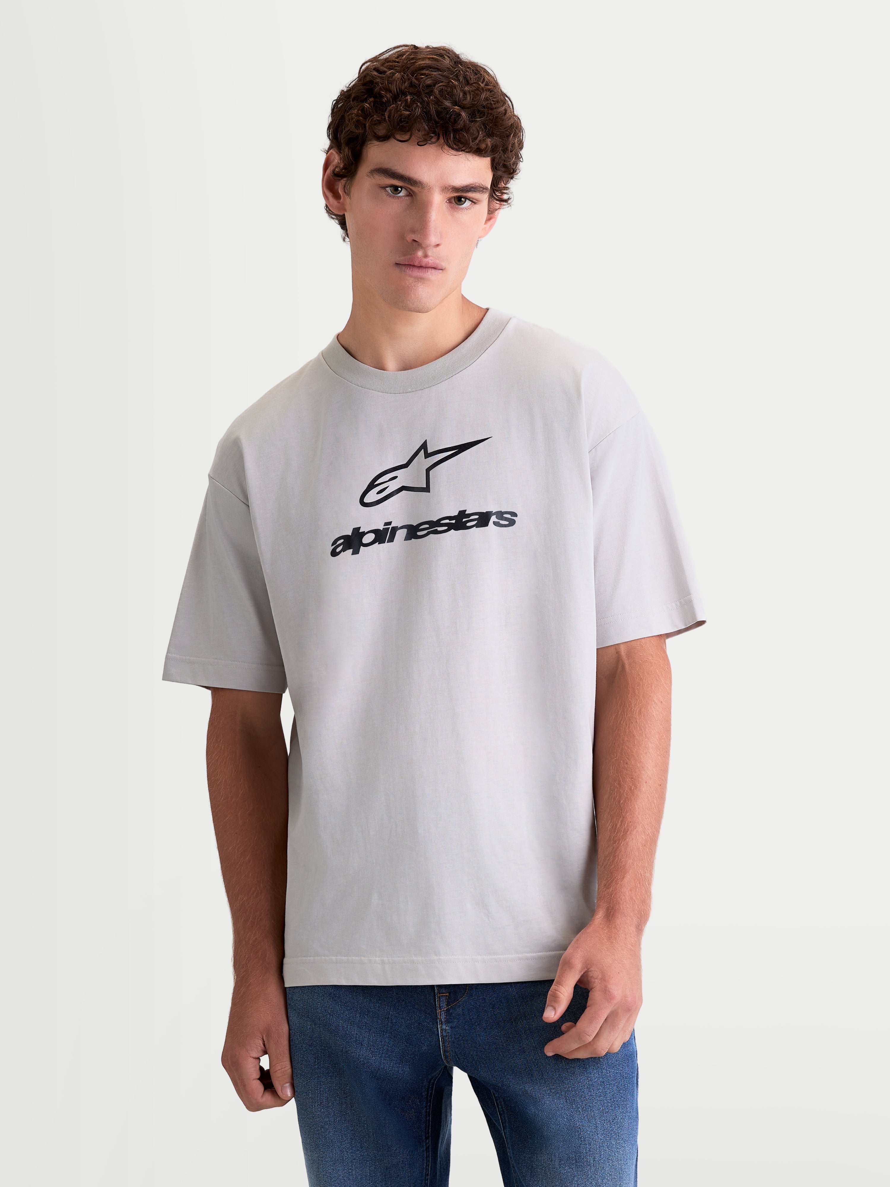 Alpinestars Prelude Oversized CSF T-shirt, sportswear-shirt met korte mouwen voor heren en dames, cementgrijs met zwart logo op de borst, relaxed fit voor casual dagelijkse stijl, vooraanzicht op model.