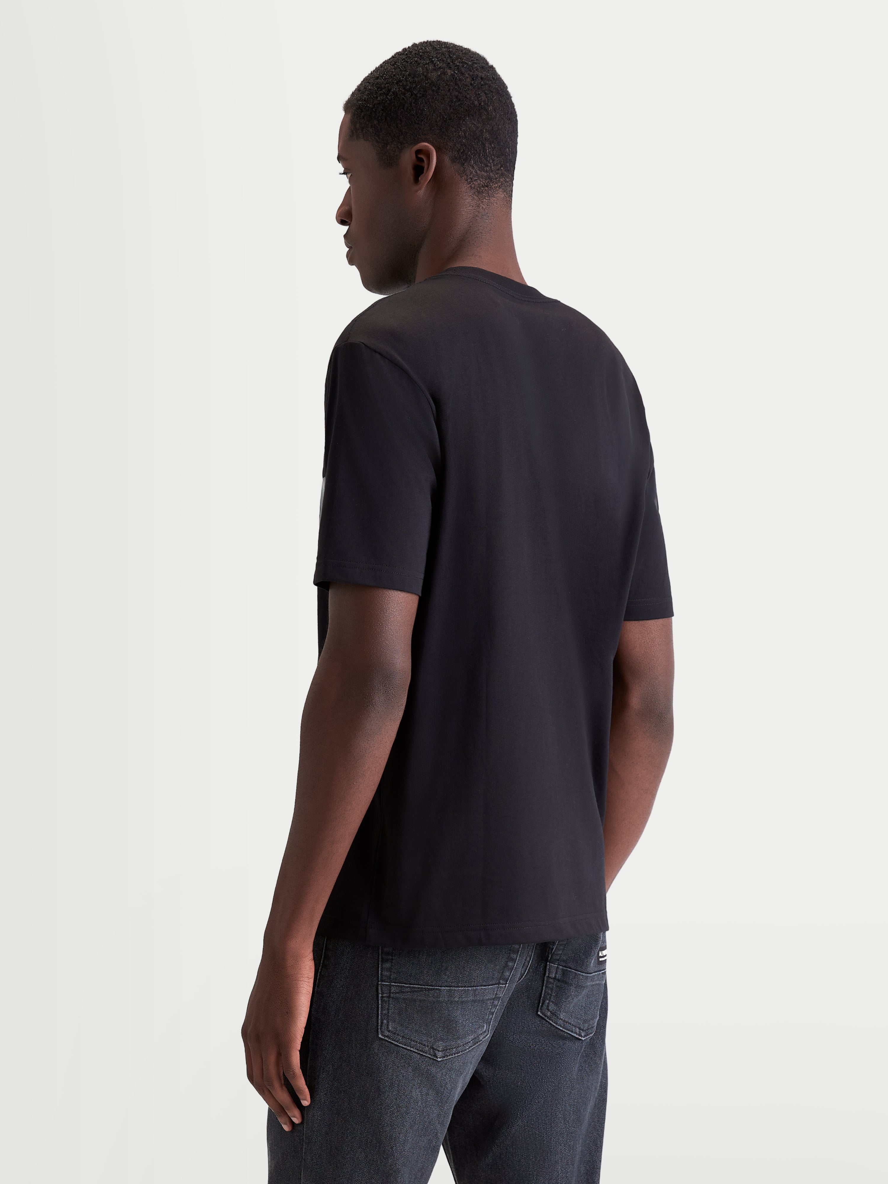 Alpinestars Singular CSF t-shirt, zwart heren-t-shirt met korte mouwen, achteraanzicht op model, vervaardigd uit een zachte katoenmix voor dagelijks motorsport-lifestylecomfort.