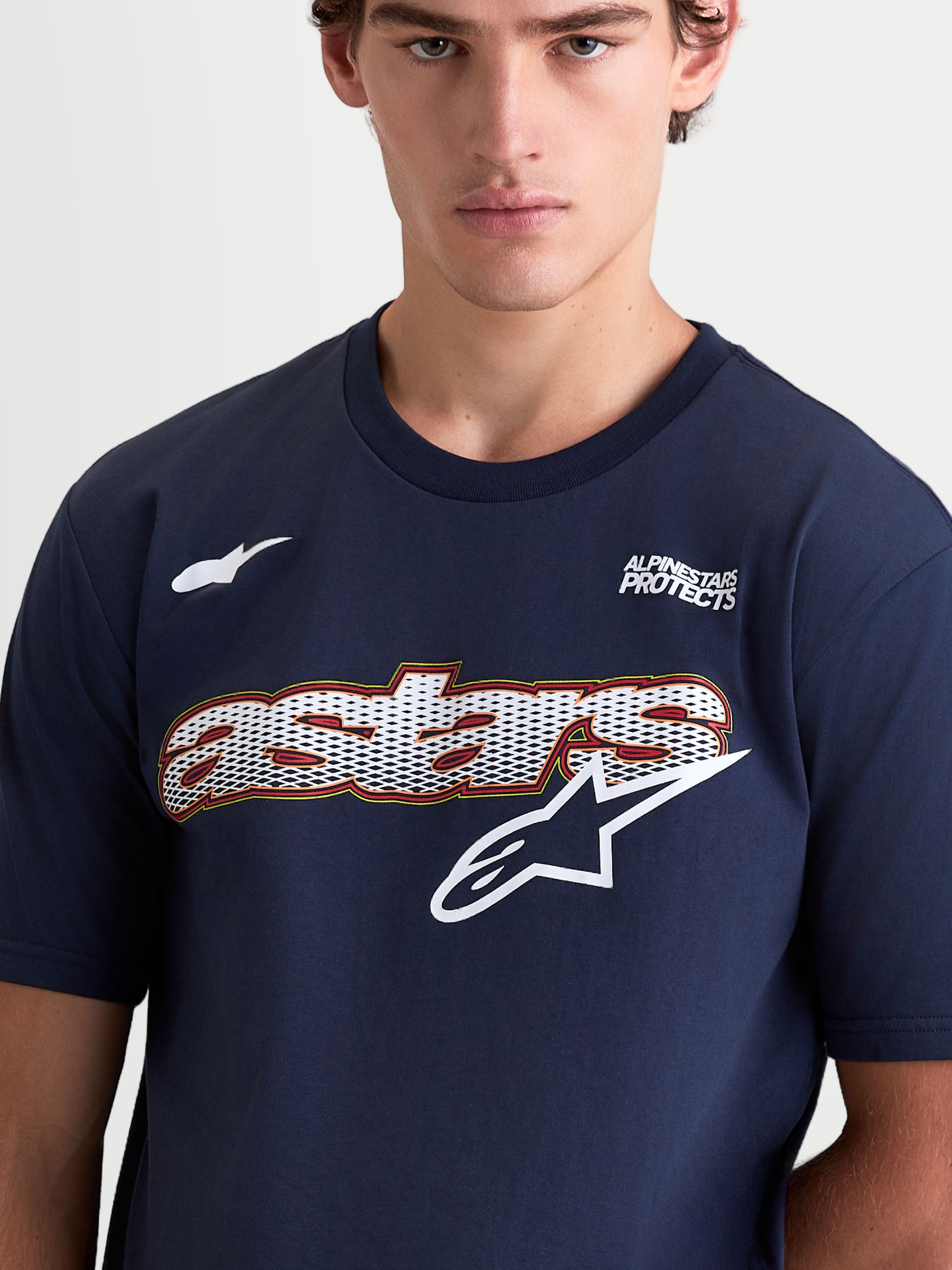 Alpinestars Cypress CSF t-shirt, heren-t-shirt met korte mouwen, marineblauw en wit, met een Astars woordgraphic met mesh-vulling en logo op de borst, Alpinestars Protects tekst, katoen-polyester blend, close-up op model.