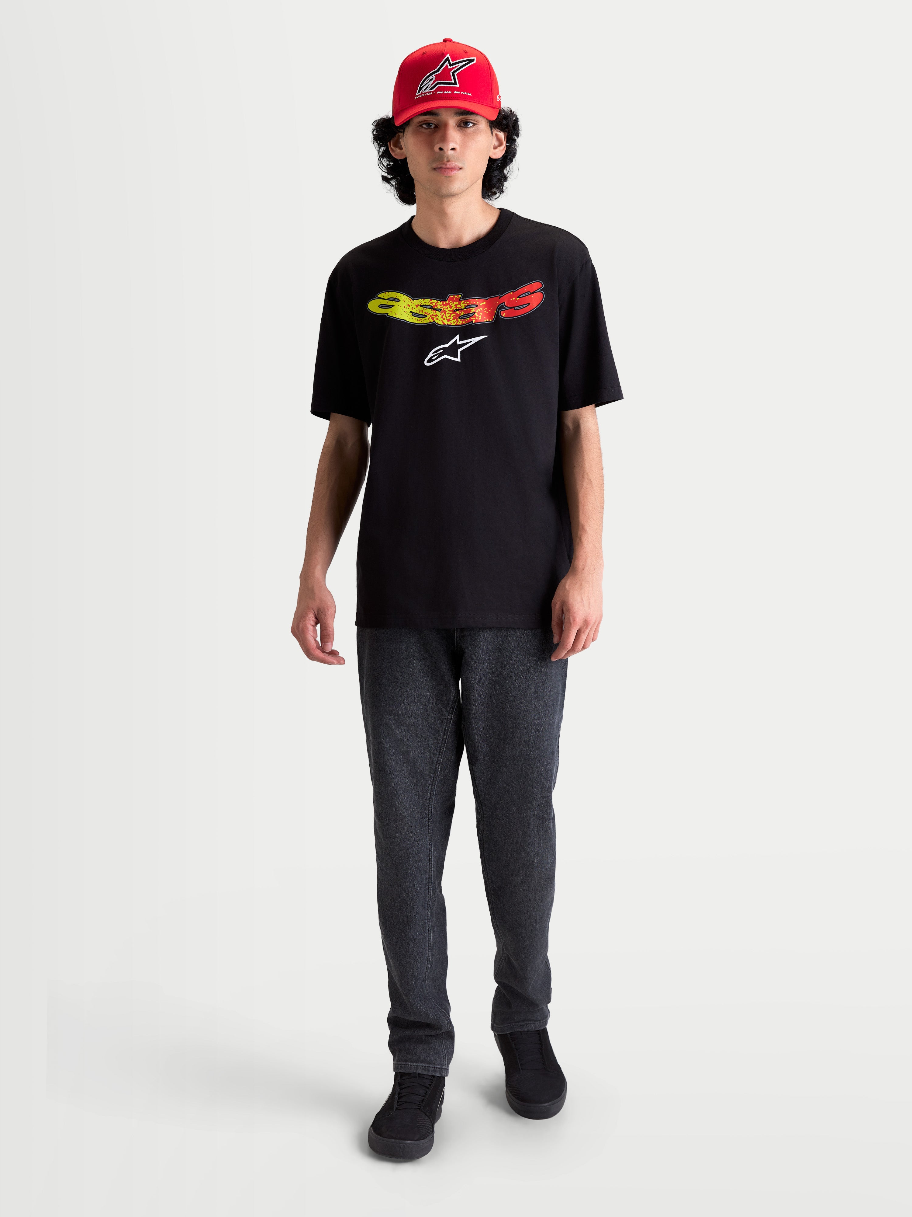 Alpinestars Elliptogrit CSF T-shirt op model, heren t-shirt met korte mouwen, zwart met geel en rood kleurverloop Astars-woordmerklogo, casual alledaagse kleding, katoen-polyestermix.