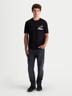 Alpinestars Lineout CSF t-shirt, heren-t-shirt met korte mouwen, zwart met wit en roze Astars-logo op de borst, op een model, zachte katoen-polyester mix, casual sportswear.