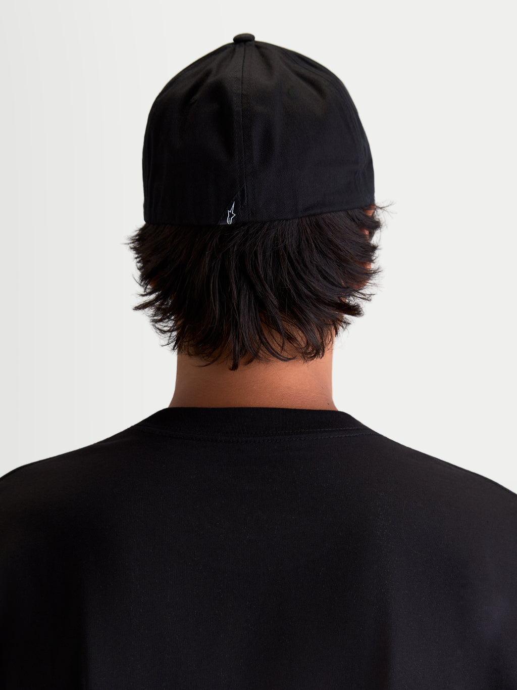 Alpinestars Arclight pet, zwarte sportswear baseballpet, achteraanzicht op model, met een klein wit Astars-logo op de achterzijde, gestructureerde kroon en flexibele achterkant, duurzaam katoenkeper voor dagelijks comfort.