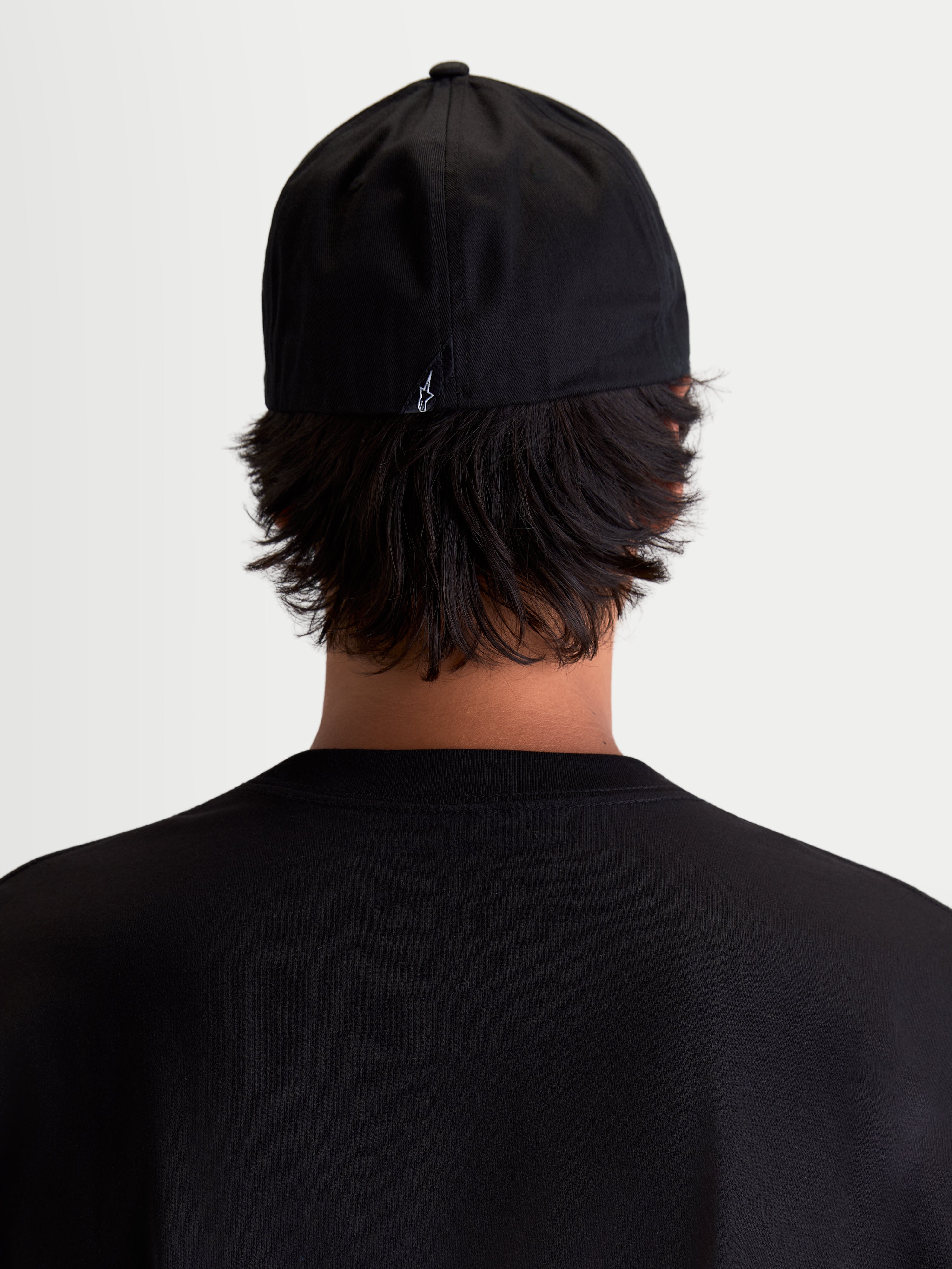 Alpinestars Arclight pet, zwarte sportswear baseballpet, achteraanzicht op model, met een klein wit Astars-logo op de achterzijde, gestructureerde kroon en flexibele achterkant, duurzaam katoenkeper voor dagelijks comfort.