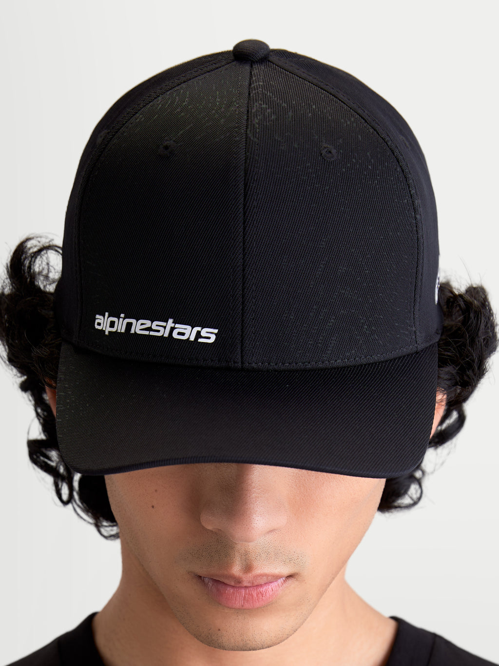 Alpinestars Points pet, zwarte sportswear-pet op model met gebogen klep, wit Alpinestars woordlogo op de voorzijde, lichtgewicht nylon tactel constructie.