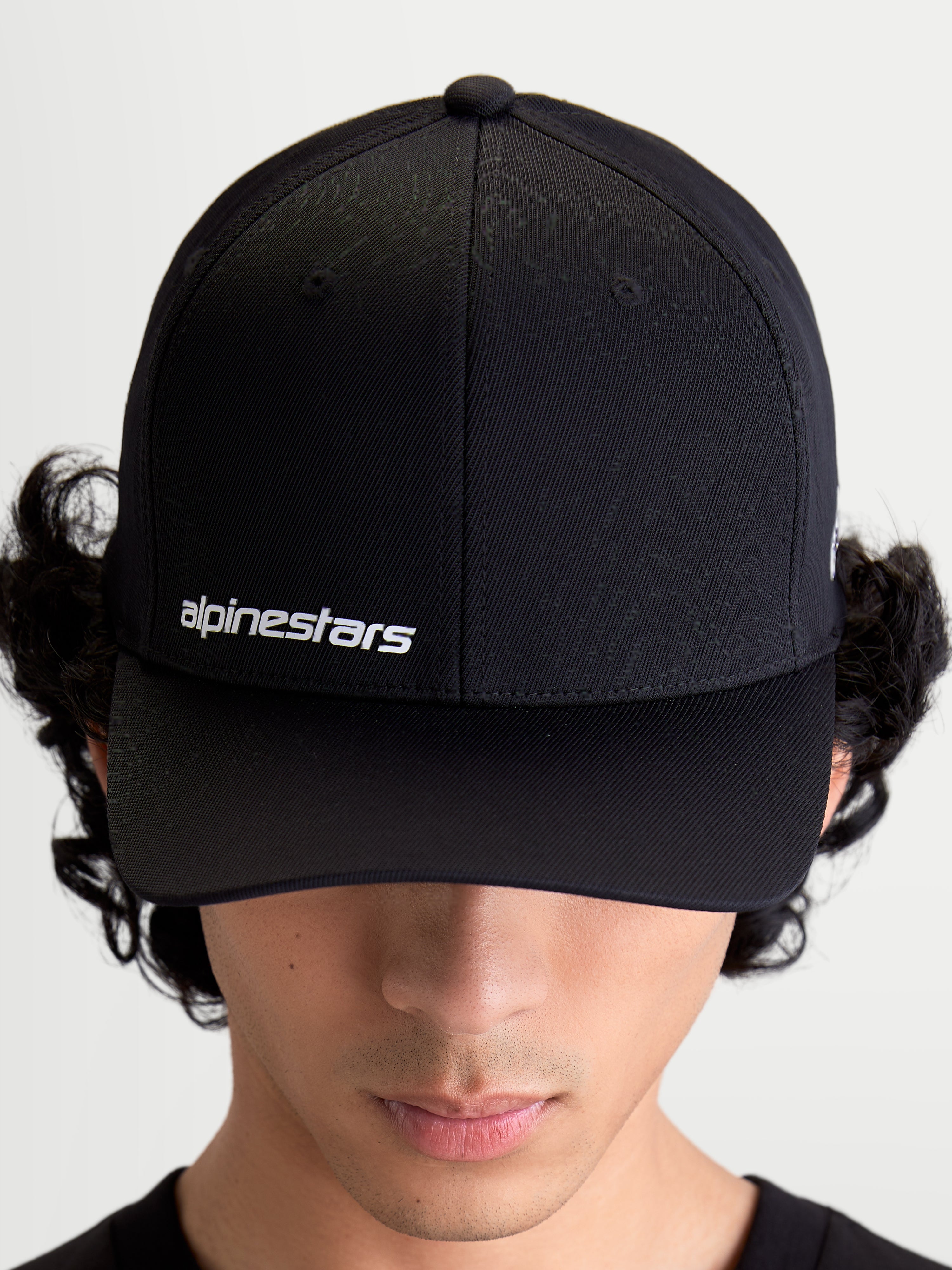 Alpinestars Points pet, zwarte sportswear-pet op model met gebogen klep, wit Alpinestars woordlogo op de voorzijde, lichtgewicht nylon tactel constructie.