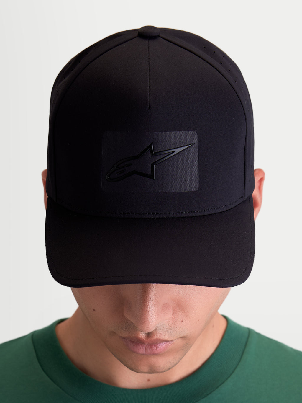 Alpinestars Algo Perf Ajustable pet, zwarte sportieve baseballpet voor heren en dames, technische stof met zijperforaties, gebogen klep en gestructureerde kroon, vooraanzicht op model met sonic-weld Astars-logo.