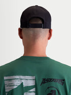 Alpinestars Algo Perf Ajustable pet, zwarte motorsport-geïnspireerde sportswear pet, achteraanzicht op model met verstelbare snapback-sluiting, technische stofconstructie, unisex.