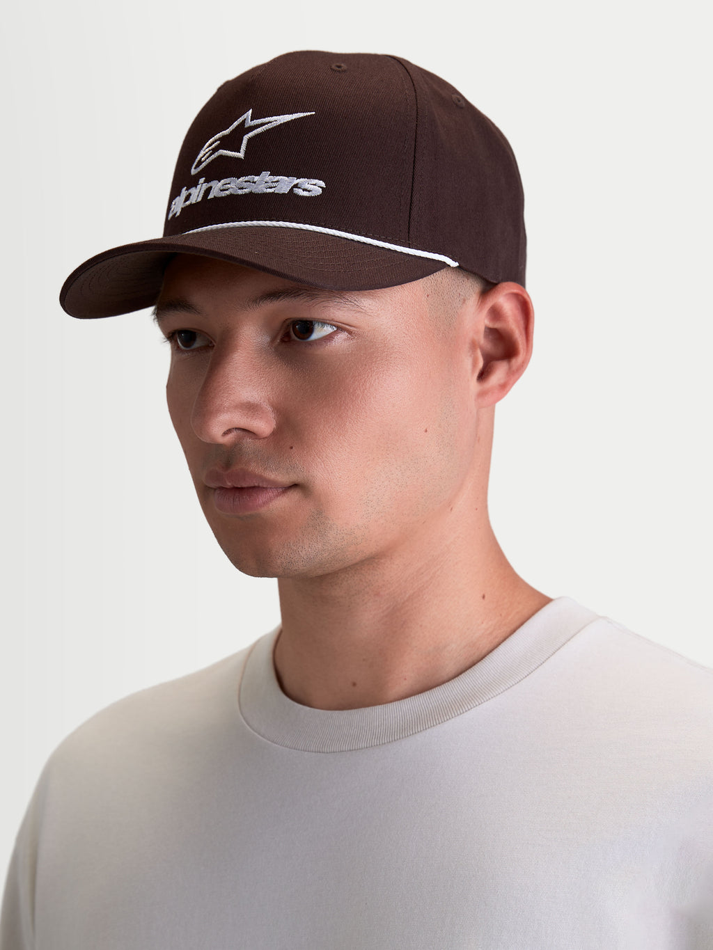 Alpinestars Combo Logo Snapback pet, bruine sportswear baseballpet voor heren, wit geborduurd logo en touwdetail, gestructureerde kroon en gebogen klep, 100% katoenen keperstof.