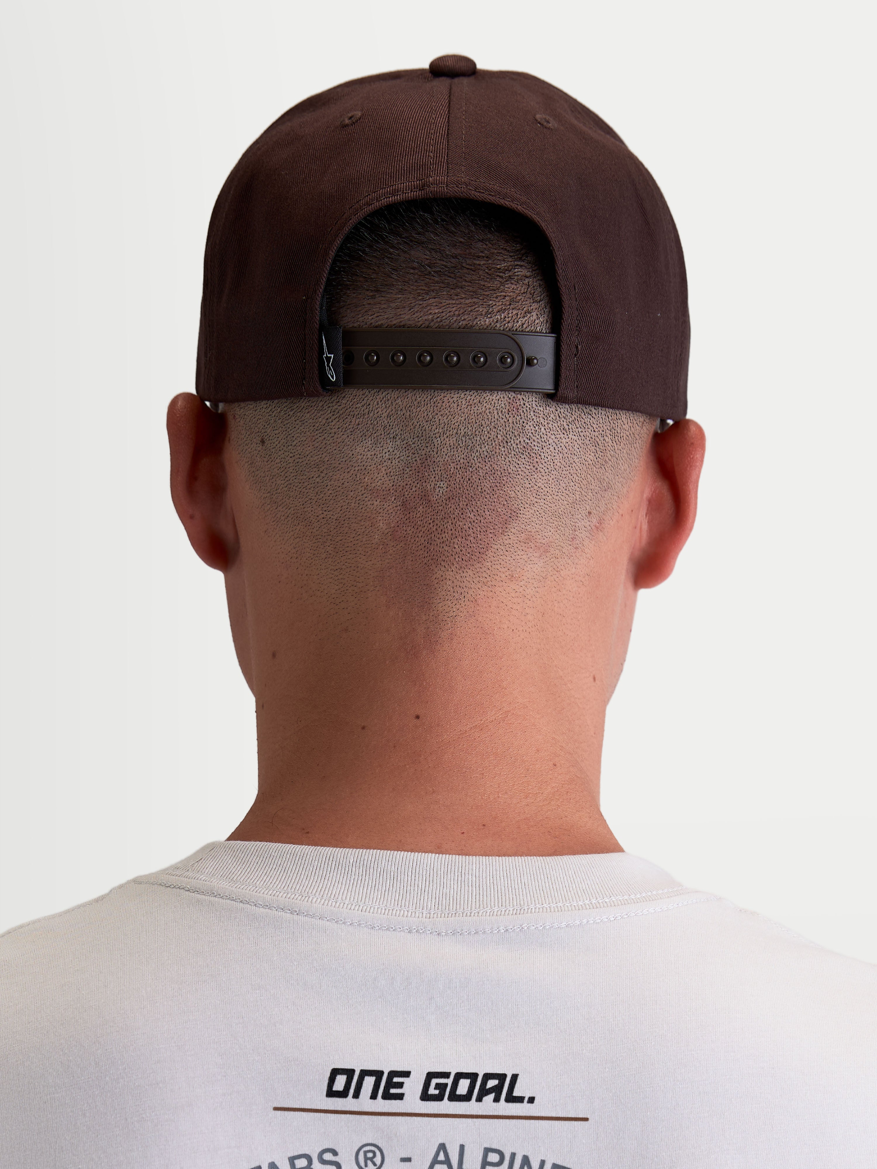 Alpinestars Combo Logo Snapback pet, casual motorsport sportswear-pet voor heren en dames, bruin, duurzame keperstof, achteraanzicht op model met verstelbare snapbacksluiting en merklabel.