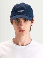Alpinestars Dylan Dad pet, casual sportswear pet in marineblauw met wit Astars-logo borduursel, gebogen klep en ongestructureerde lage kroon gedragen door een model