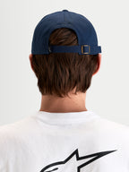 Alpinestars Dylan Dad Pet, casual sportswear pet in donkerblauw, achteraanzicht met verstelbare bandsluiting en metalen gesp gedragen door een model