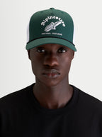 Alpinestars Baron Trucker Hat, green and white casual lifestyle hat, curved bill with structured crown and mesh back, worn by a model